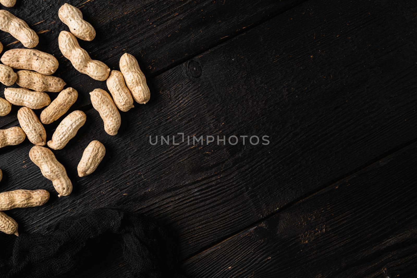 Organic peanuts in shell set, on black wooden table background, top view flat lay, with copy space for text