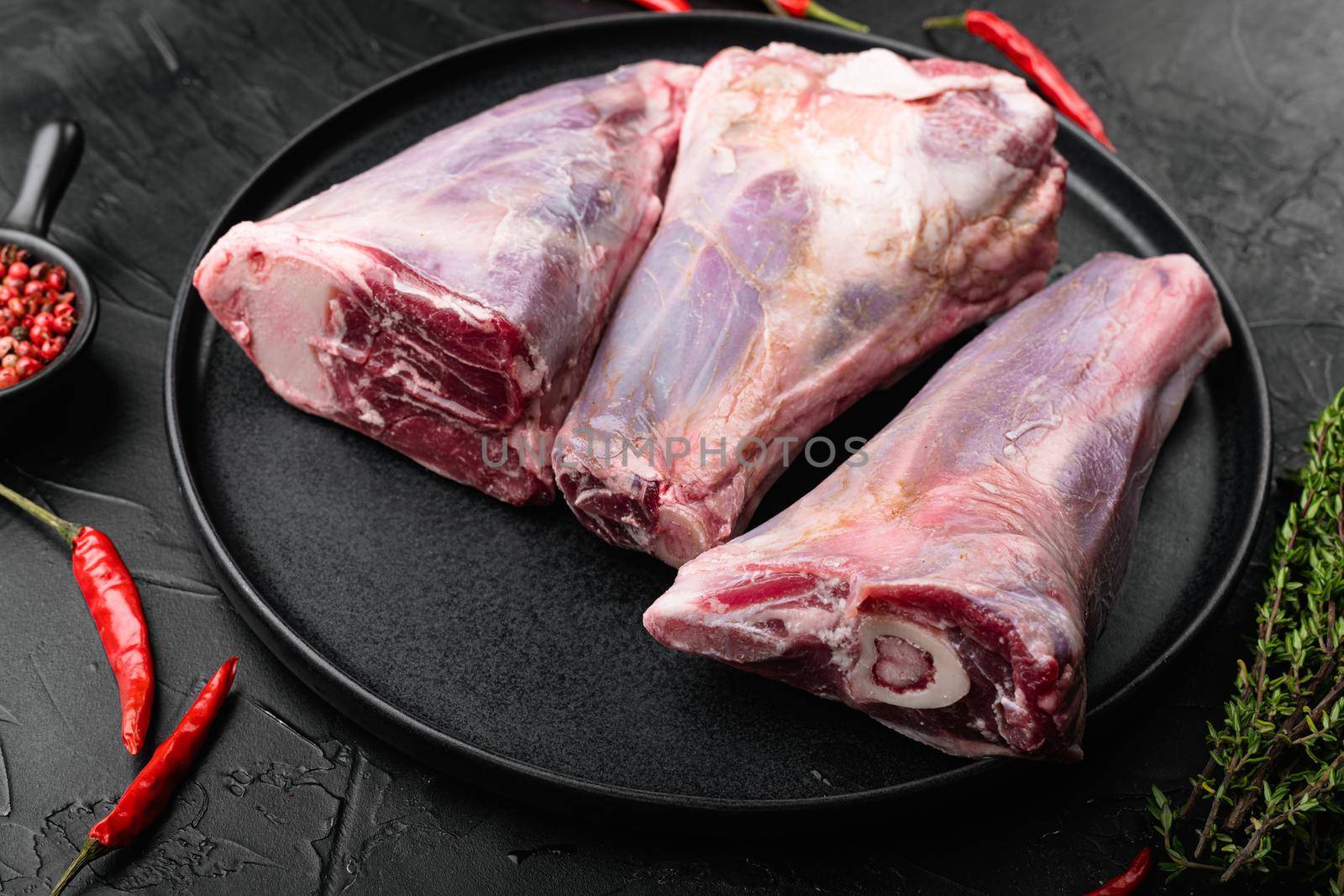 Raw lamb shanks meat set, on black dark stone table background