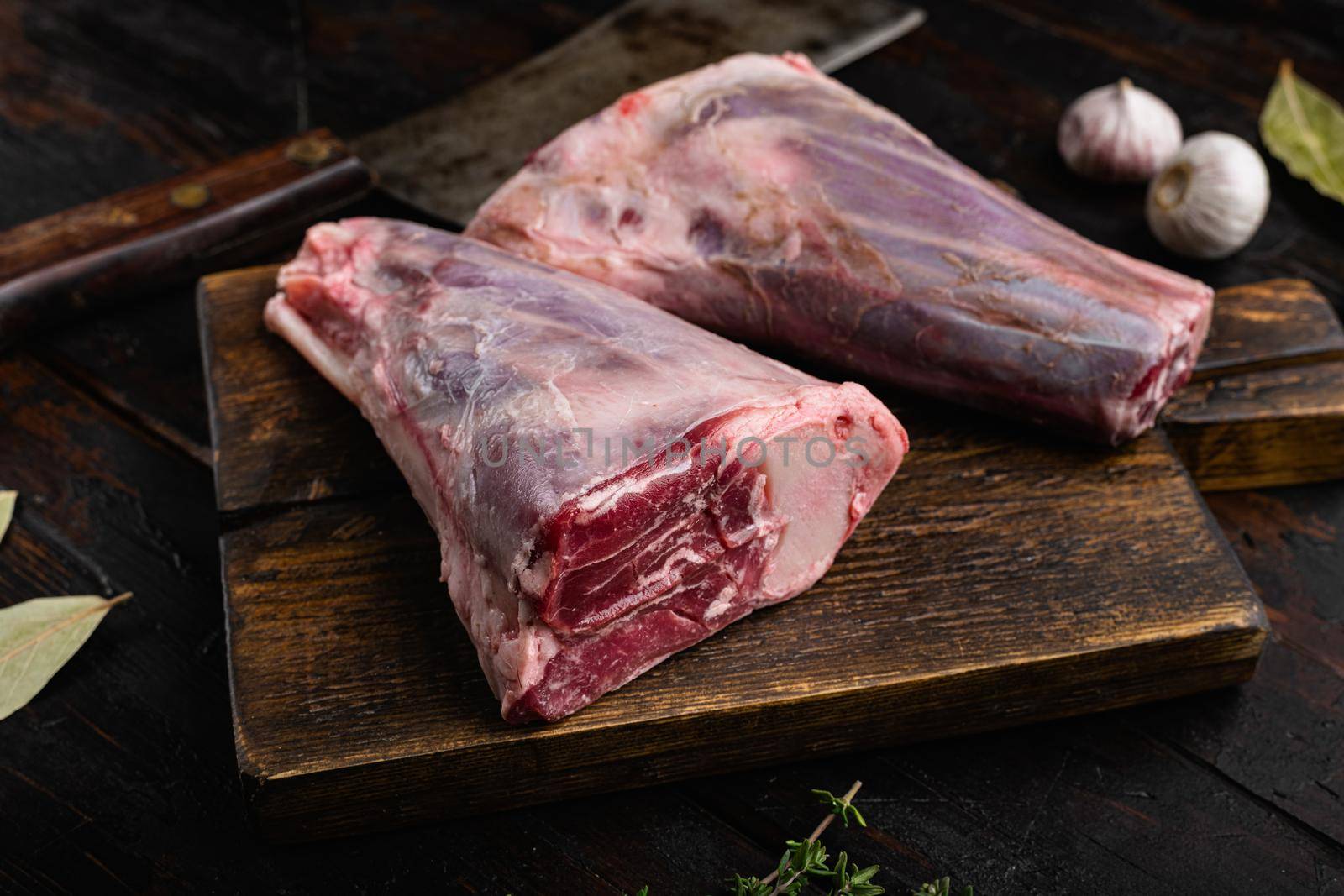 Raw lamb shanks with ingredients set, on old dark wooden table background