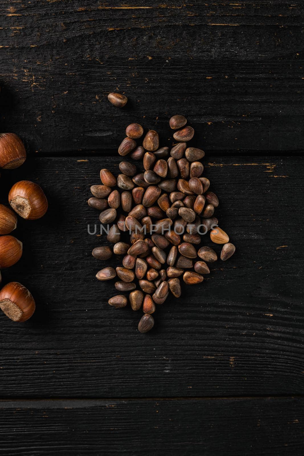 Pine nuts, on black wooden table background, top view flat lay, with copy space for text by Ilianesolenyi