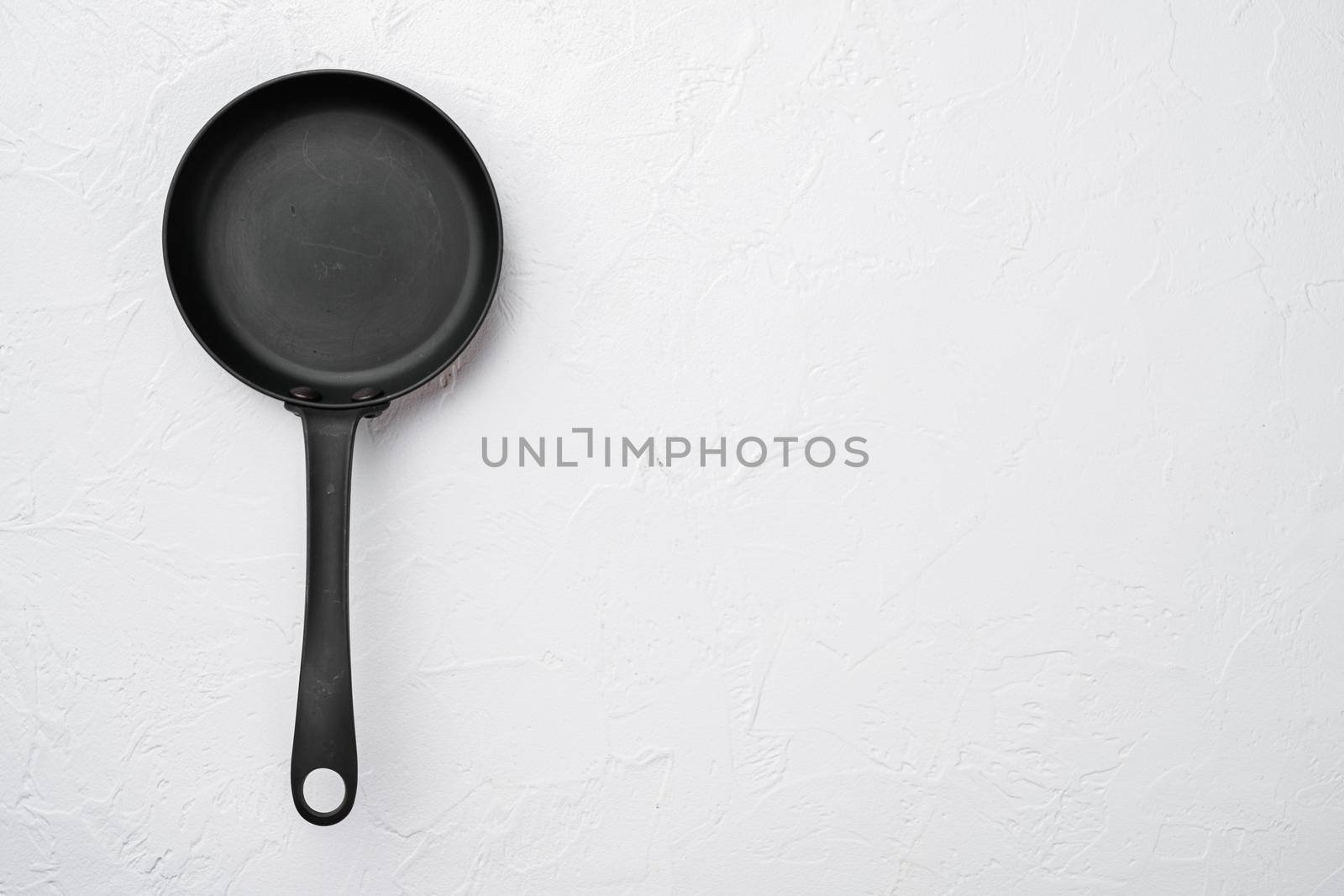 Large frying pan set with copy space for text or food with copy space for text or food, top view flat lay, on white stone table background