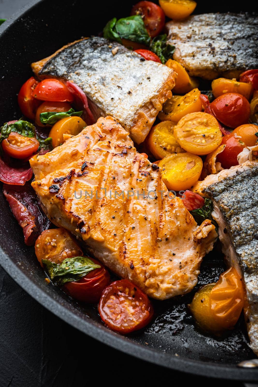 Smoky chorizosalmon grilled with cherry tomatoes on black background.