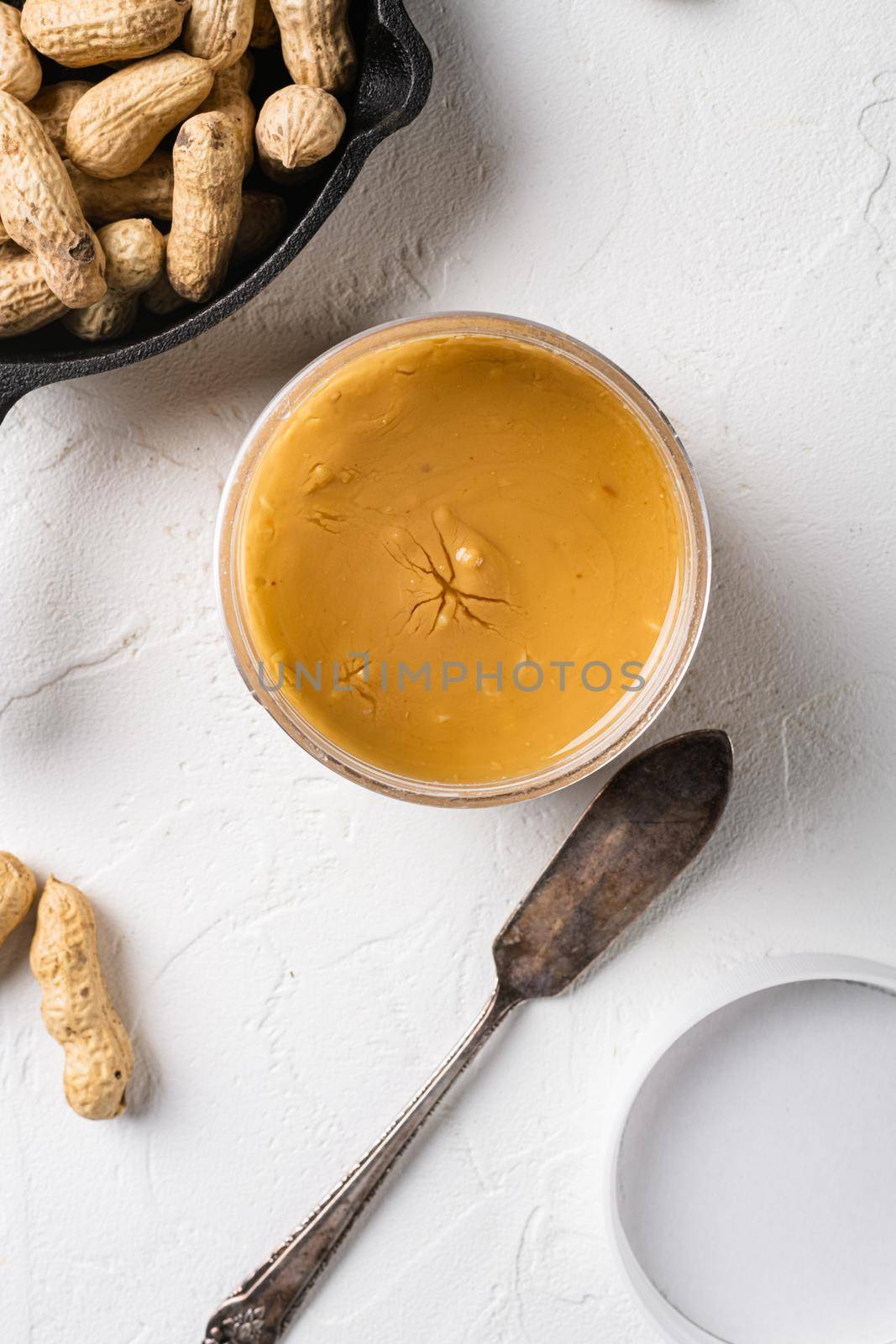 Creamy and smooth peanut butter in jar, on white stone table background, top view flat lay by Ilianesolenyi