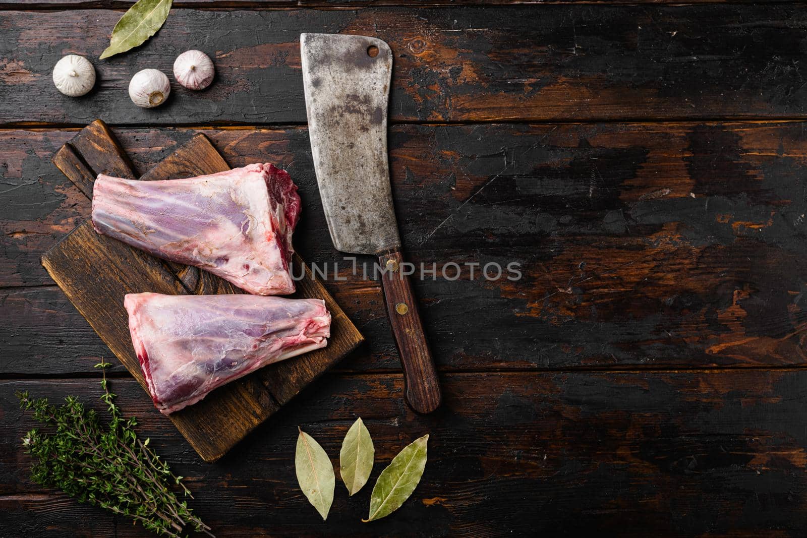 Uncooked lamb shank set, on old dark wooden table background, top view flat lay, with copy space for text