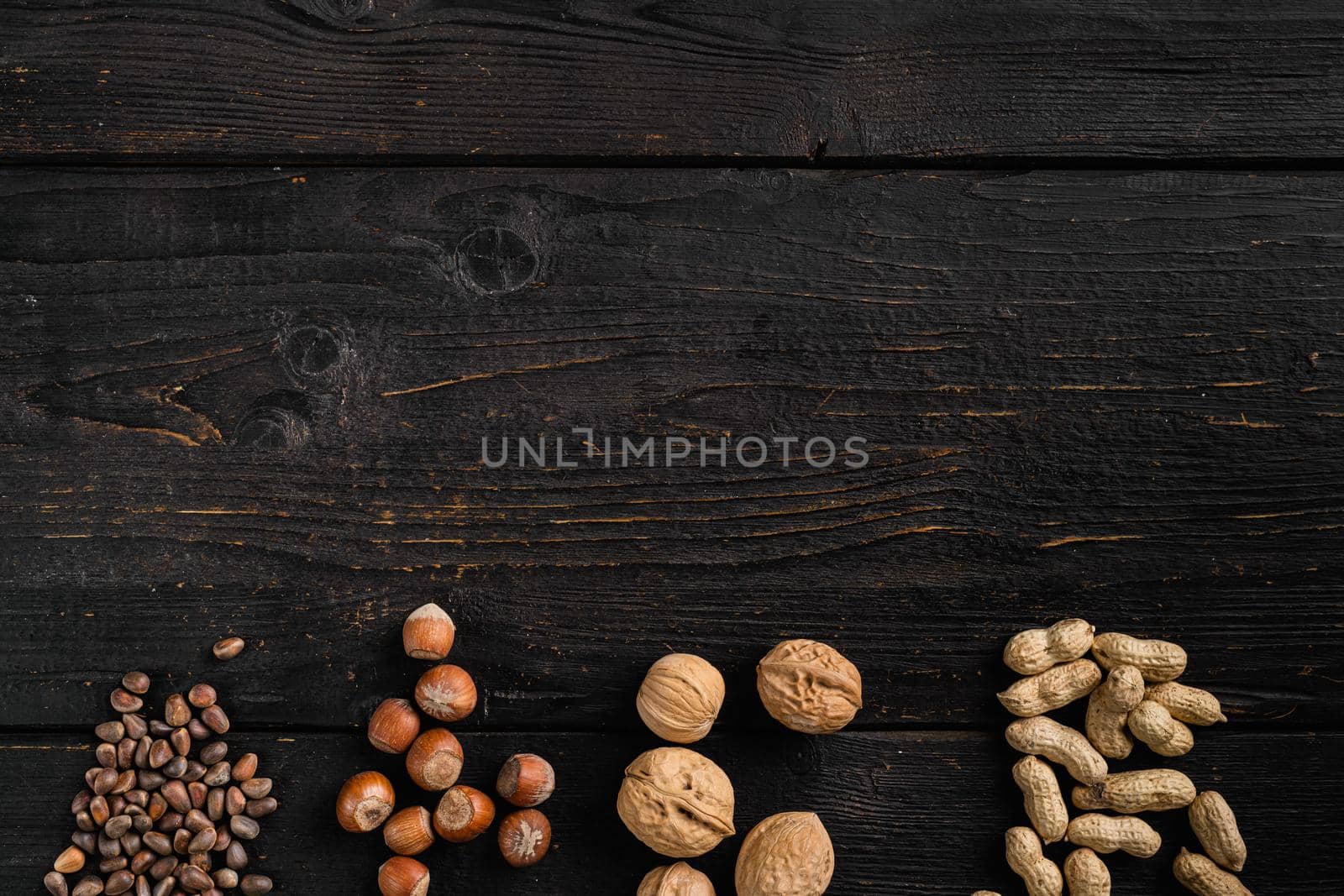 Nuts mix, peanut, walnut, pine nuts and hazelnut set, on black wooden table background, top view flat lay, with copy space for text