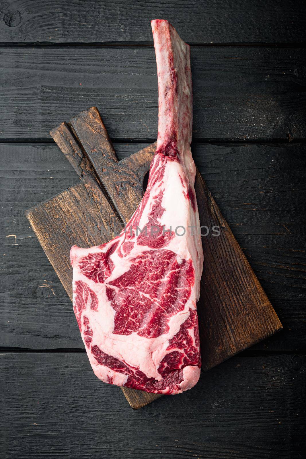 Tomahawk raw fresh beef steak with spices, on black wooden table background, top view flat lay by Ilianesolenyi