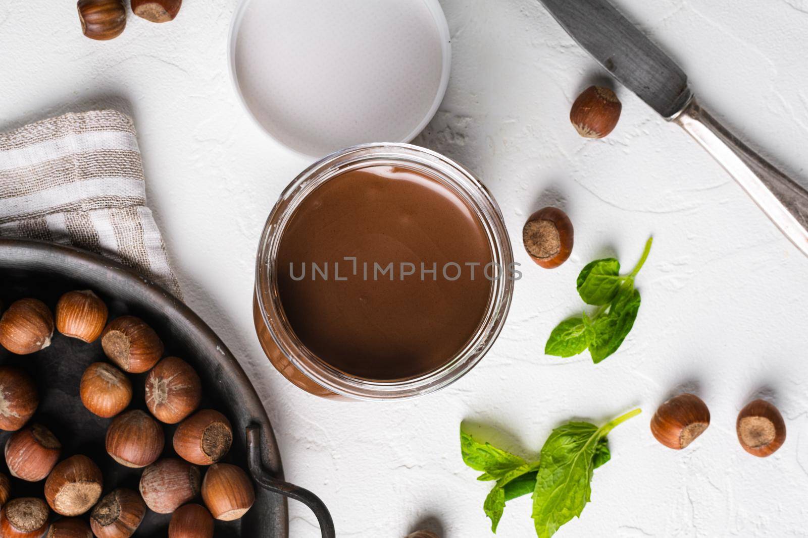 Chocolate spread or nougat cream with hazelnut set, on white stone table background, top view flat lay