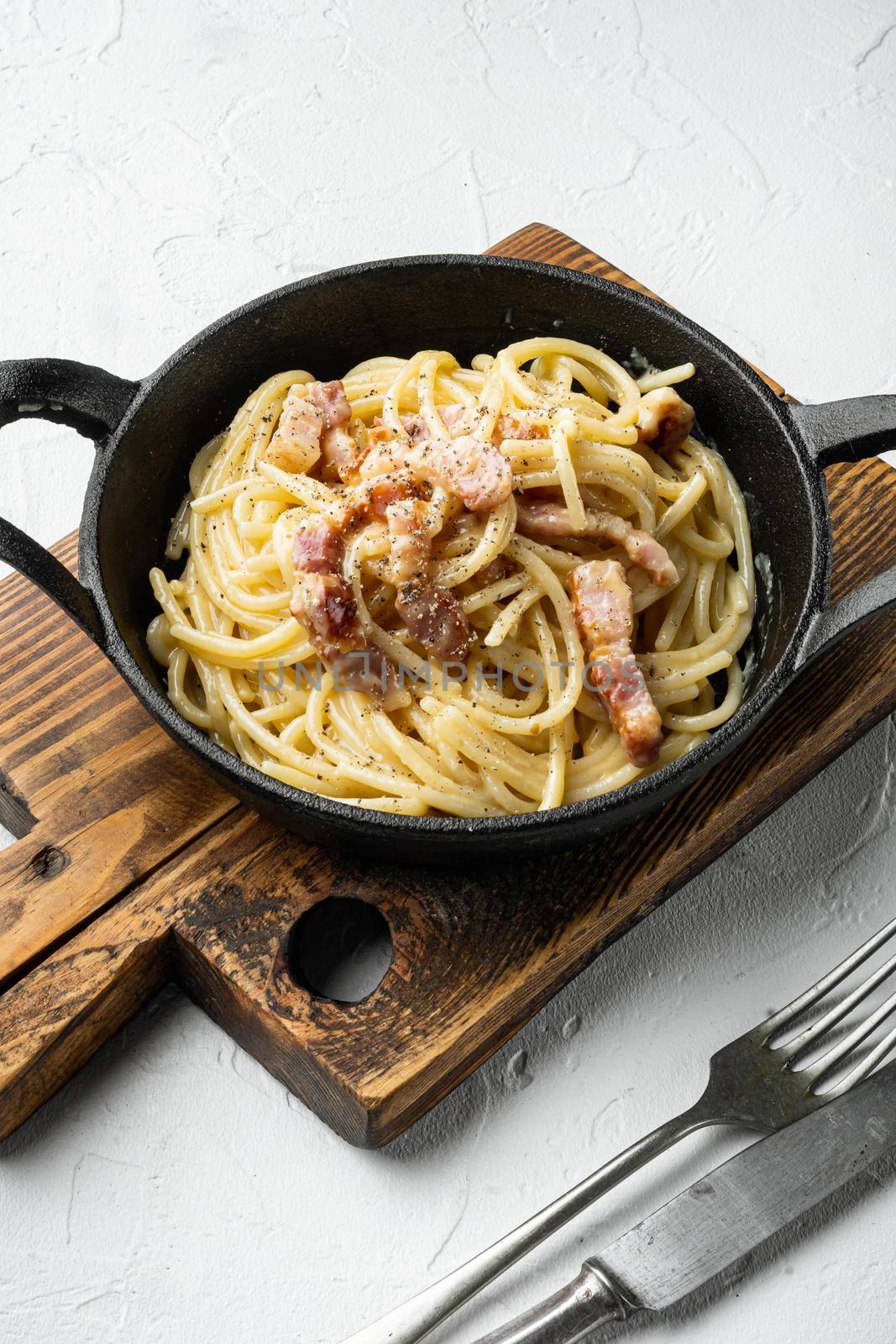 Classic Homemade Pasta carbonara Italian with Bacon, eggs, Parmesan Cheese set, in cast iron frying pan, on white stone surface