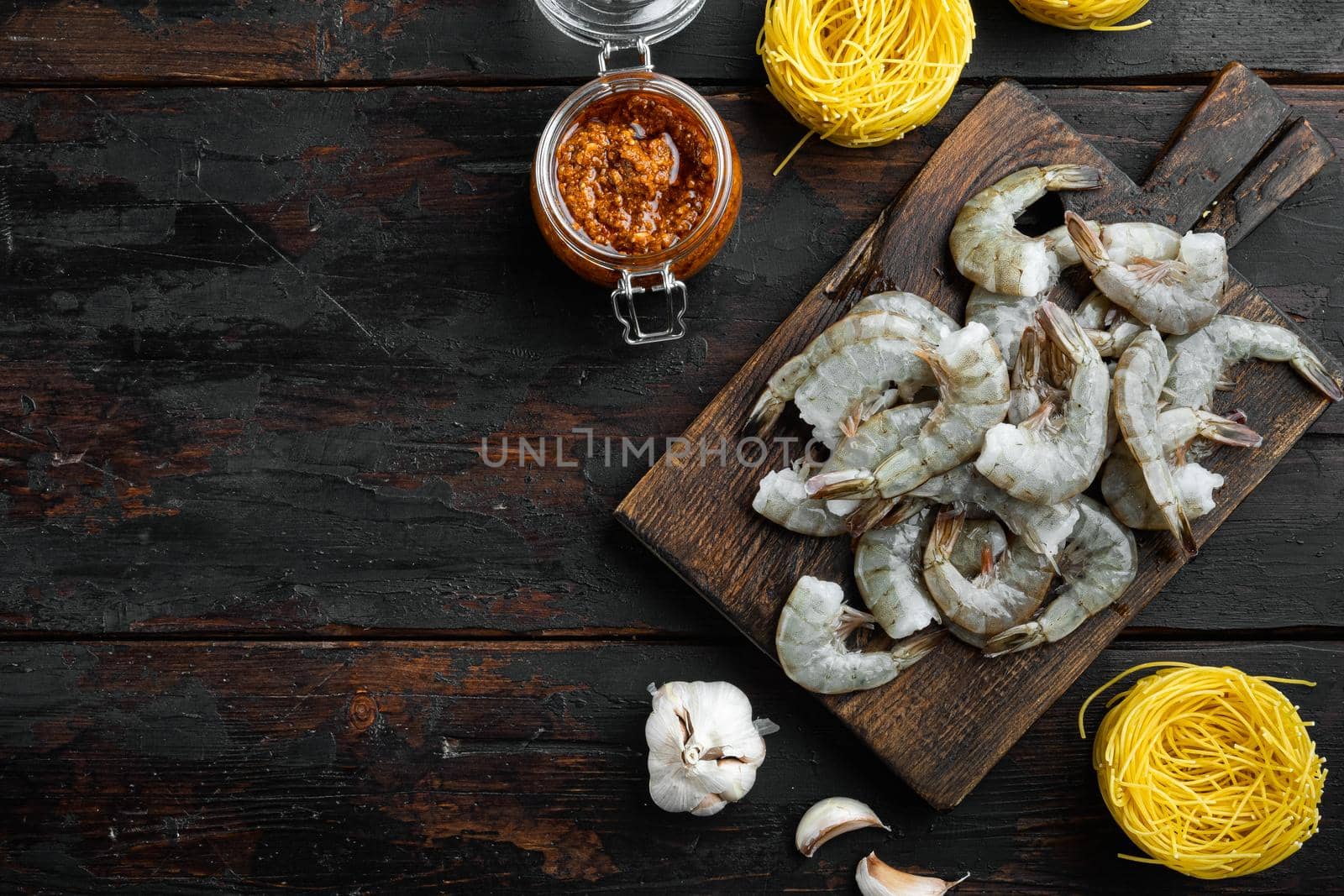 Pasta with shrimp, tomato and pesto sauce ingredients, on old dark wooden table , top view flat lay, with copy space for text by Ilianesolenyi