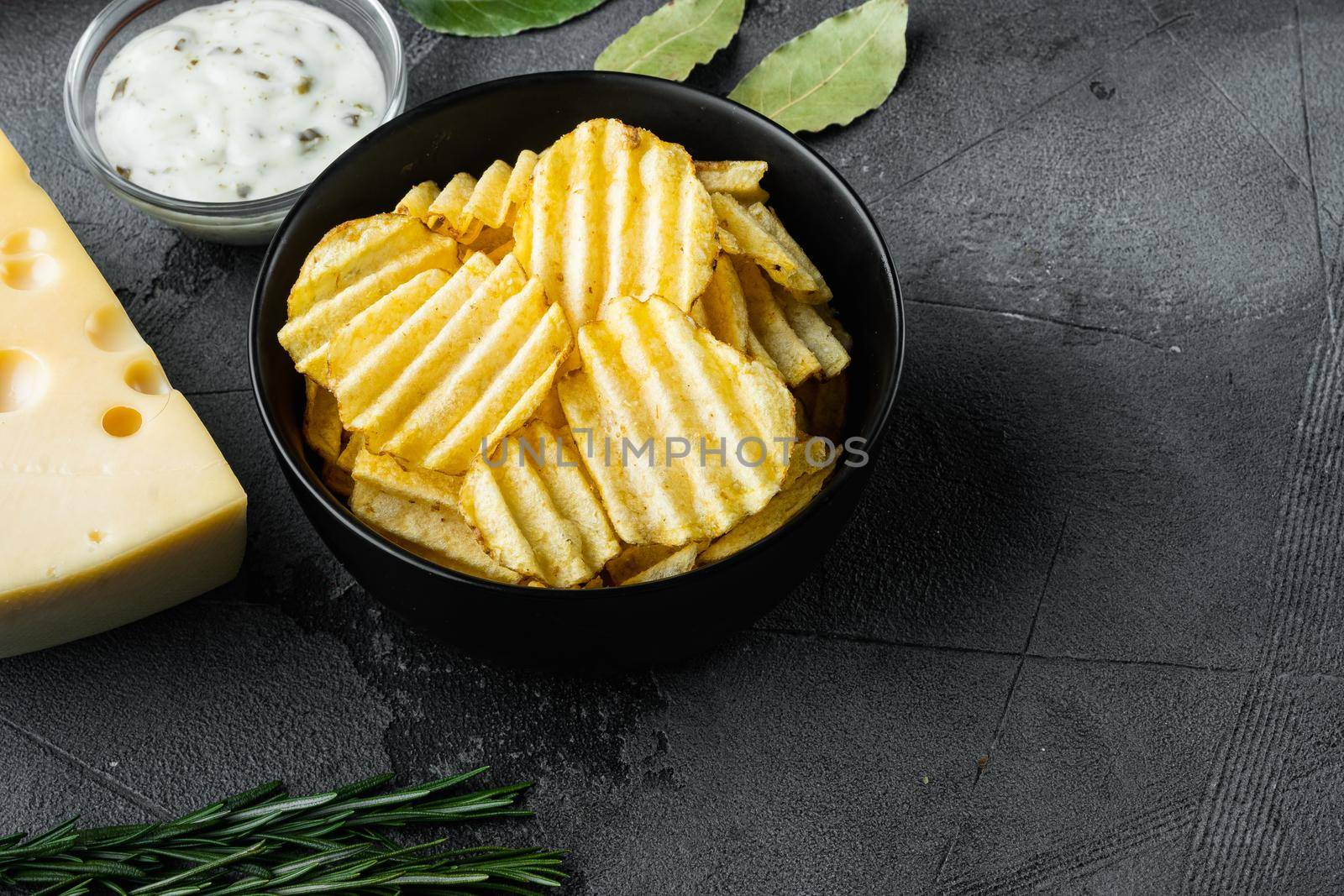 Salty potato chips snack with Cheese and Onion, with dipping sauces , on gray stone background, with copy space for text by Ilianesolenyi