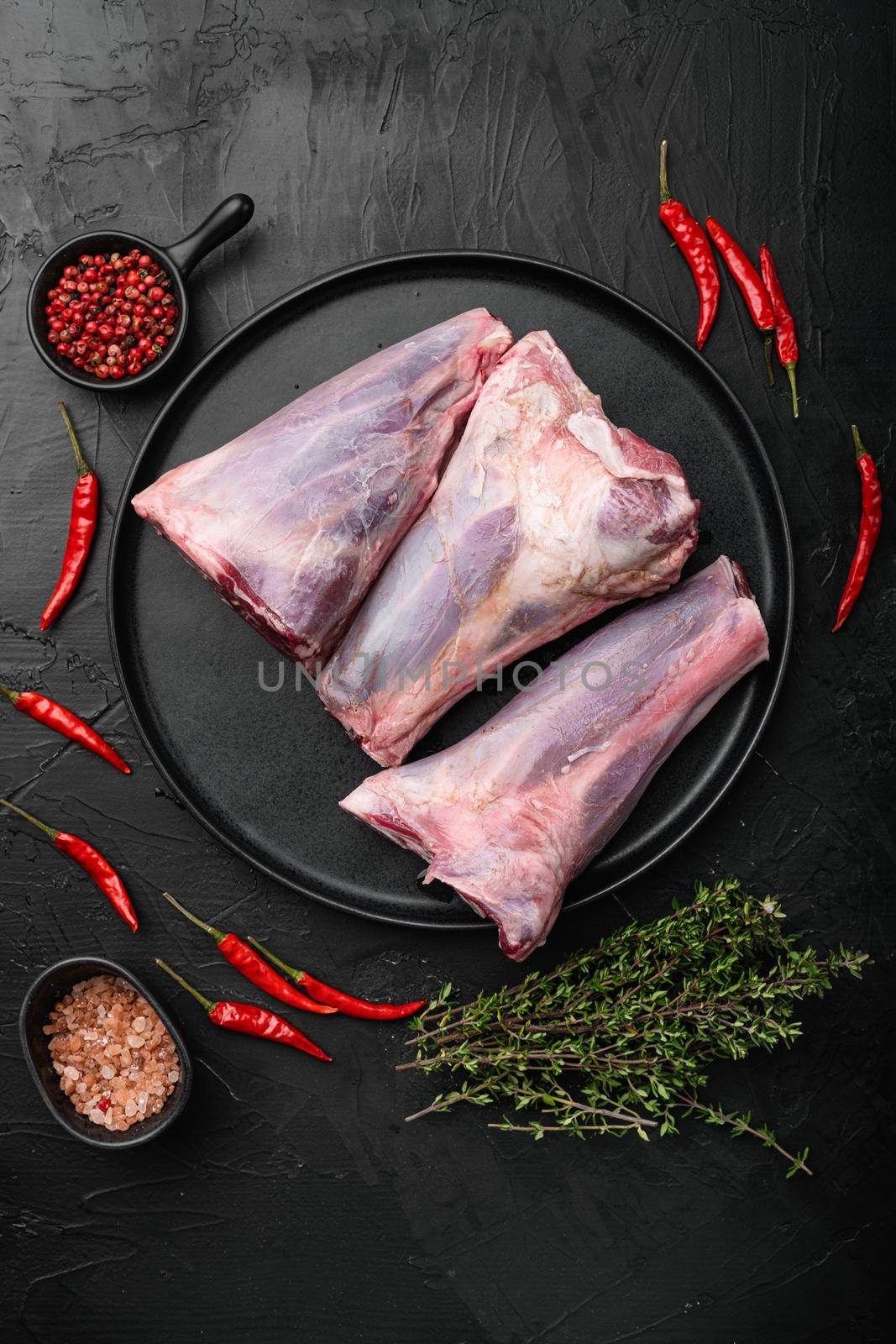 Fresh lamb shank, on black dark stone table background, top view flat lay by Ilianesolenyi