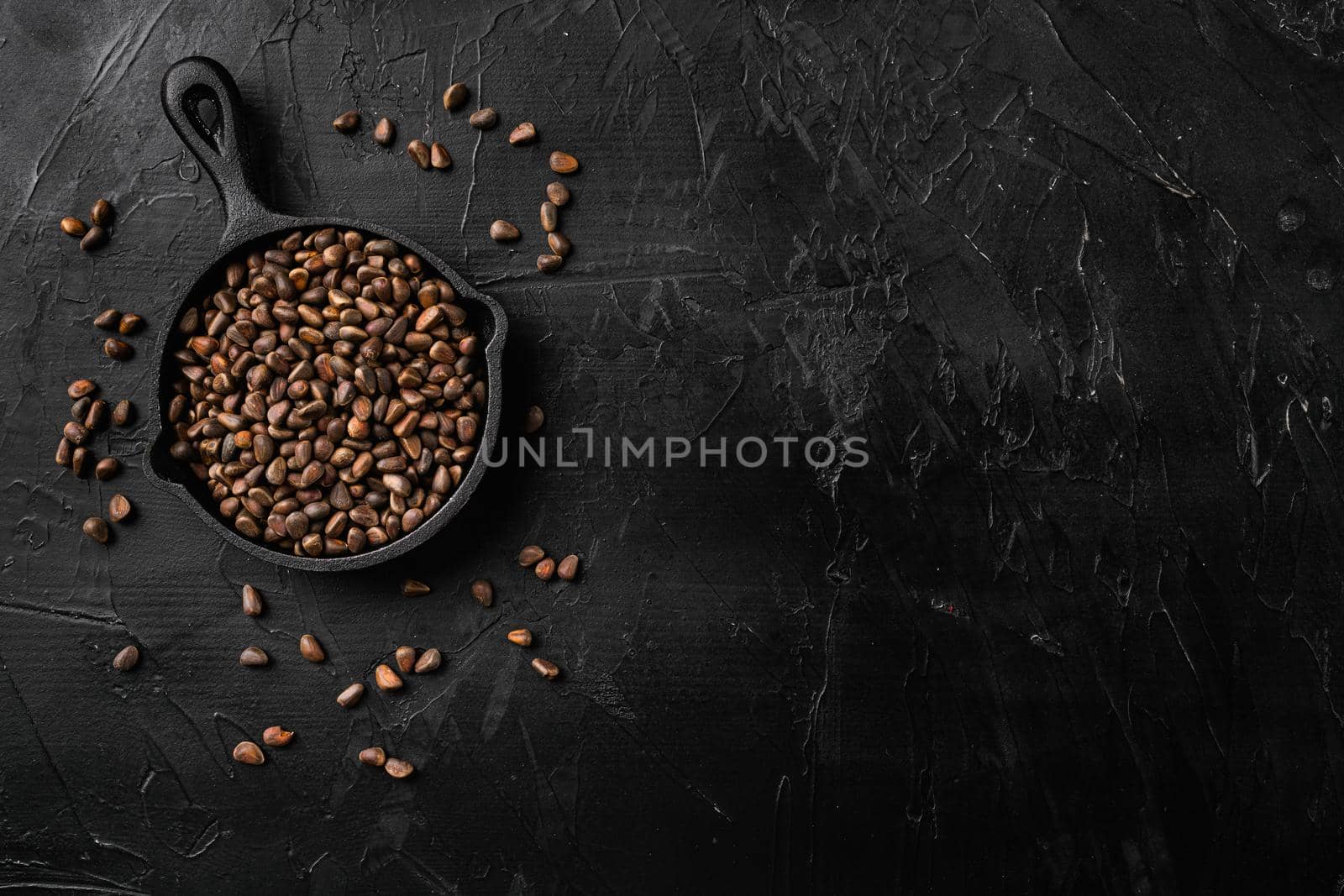 Pine nuts, on black dark stone table background, top view flat lay, with copy space for text by Ilianesolenyi