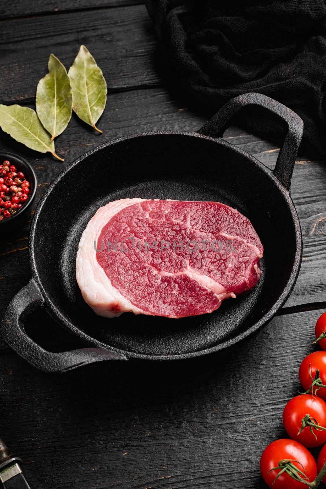 Raw tenderloin steak, on black wooden table background by Ilianesolenyi