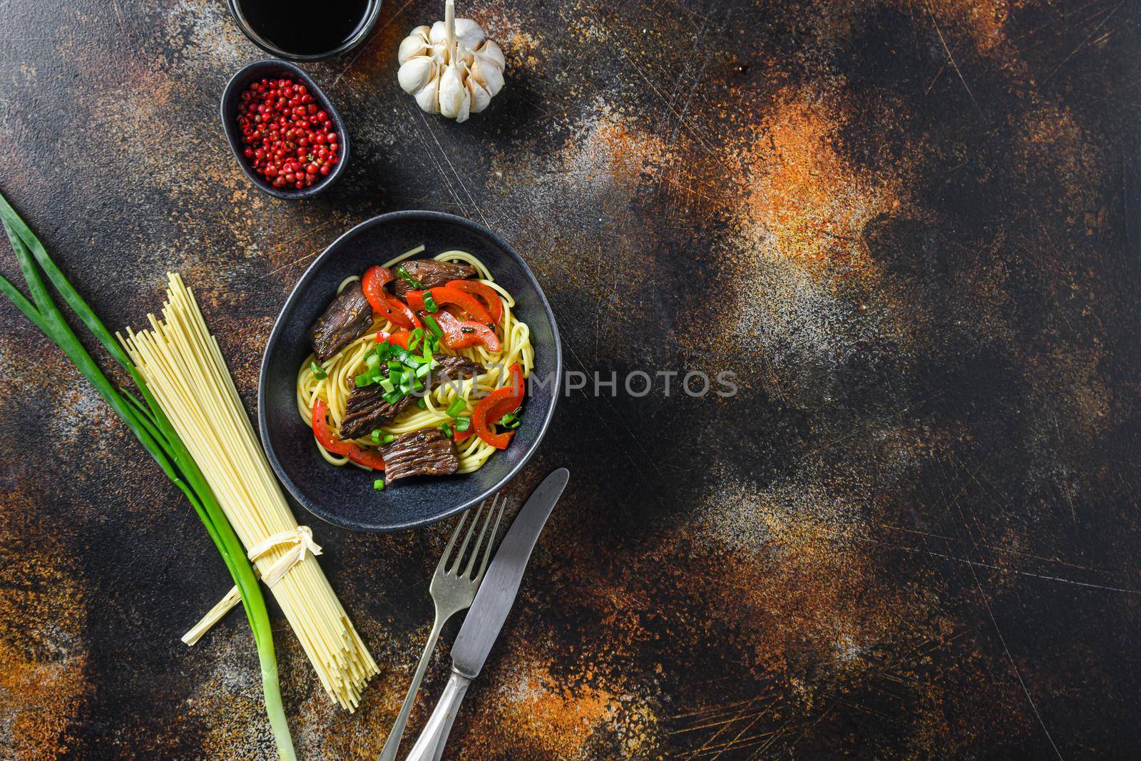 Chinese noodles with vegetables and beef in black bowl top view. Space for text. by Ilianesolenyi