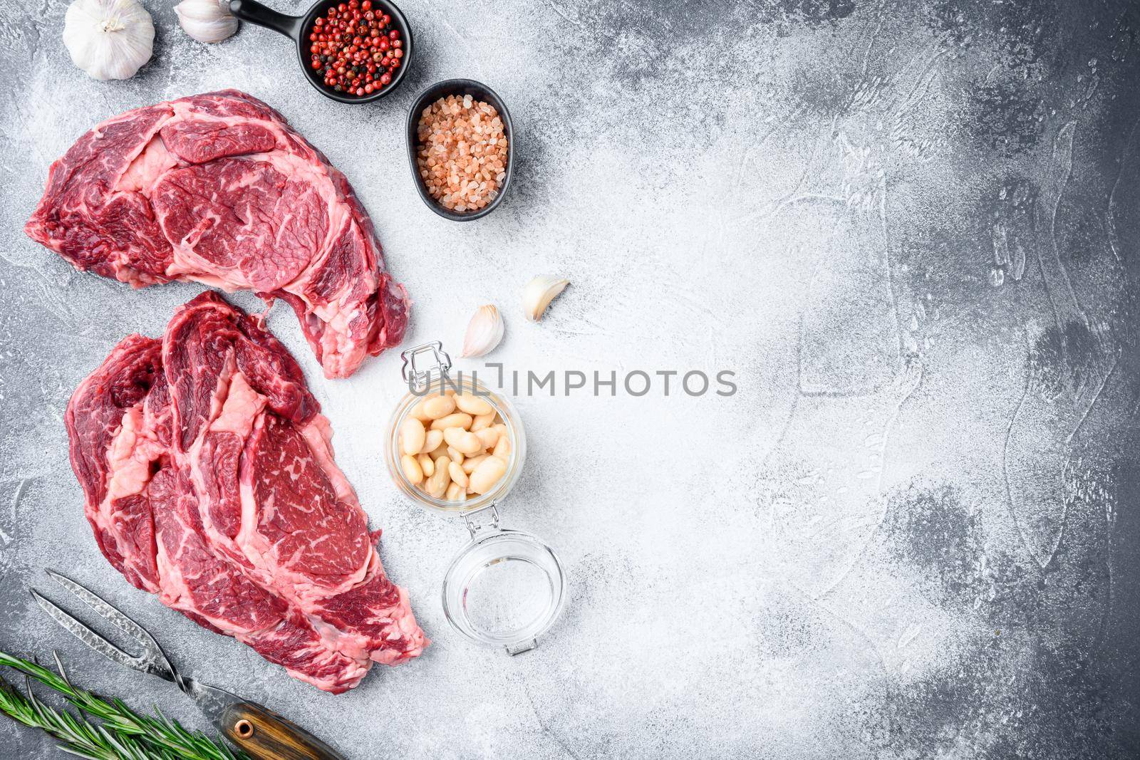 Rib eye steak of beef marbled meat or scotch fillet set, on gray stone background, top view flat lay, with copy space for text