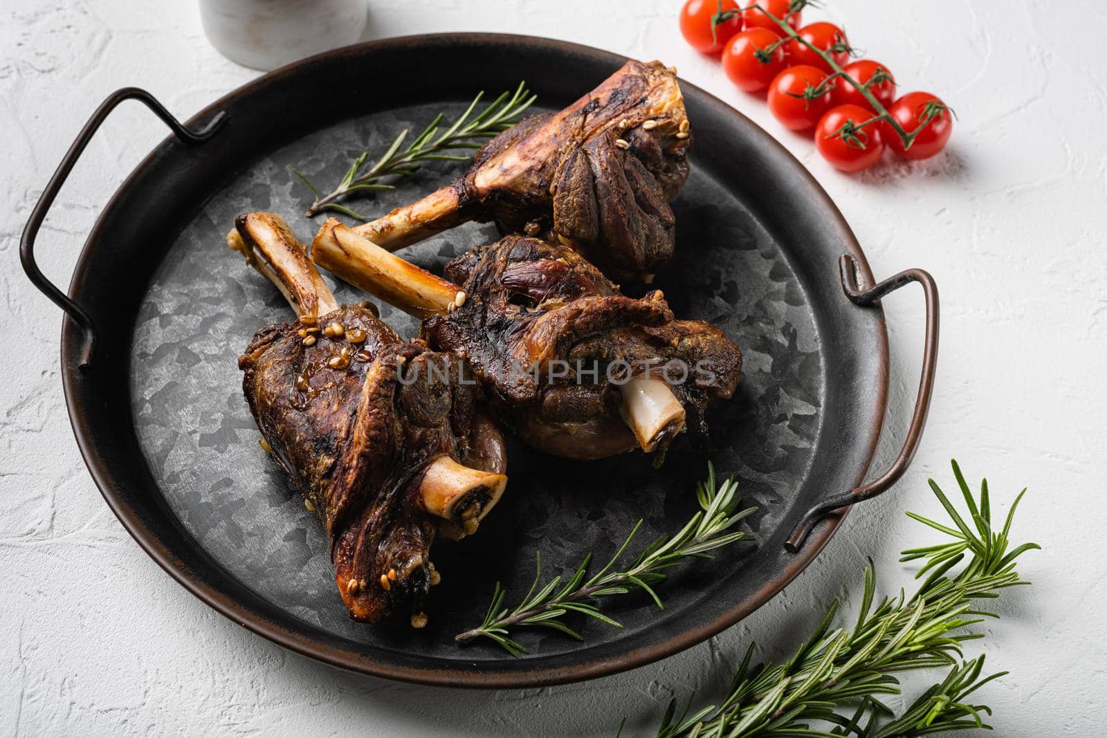 Baked lamb shank with barley and ale set, on white stone table background