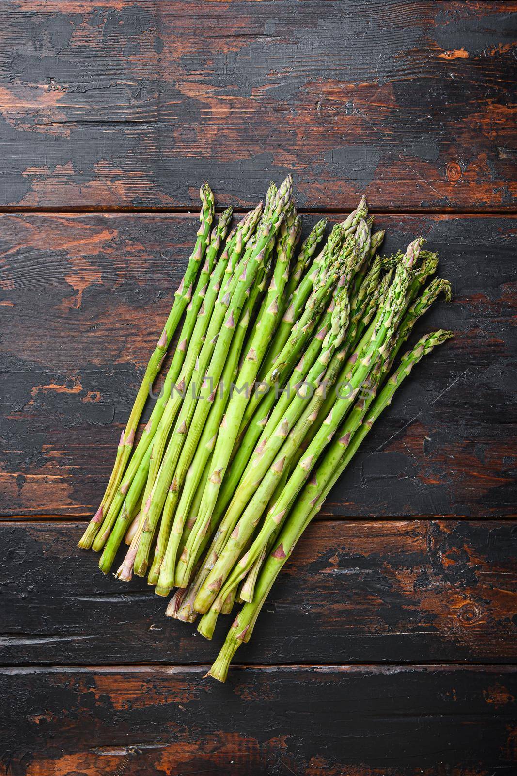 Raw organic asparagus on dark wooden old background, top view