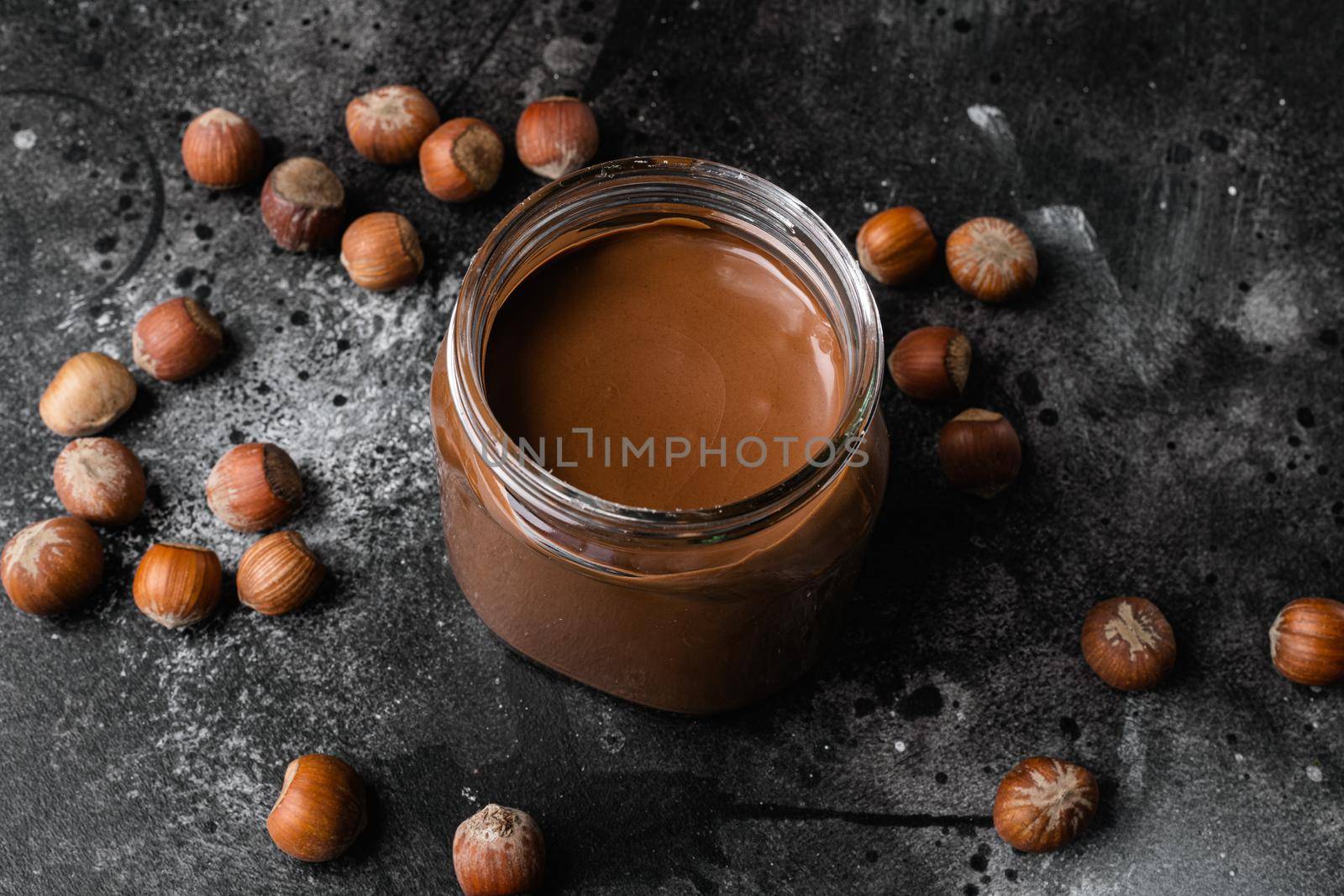 Chocolate spread or nougat cream with hazelnut set, on black dark stone table background