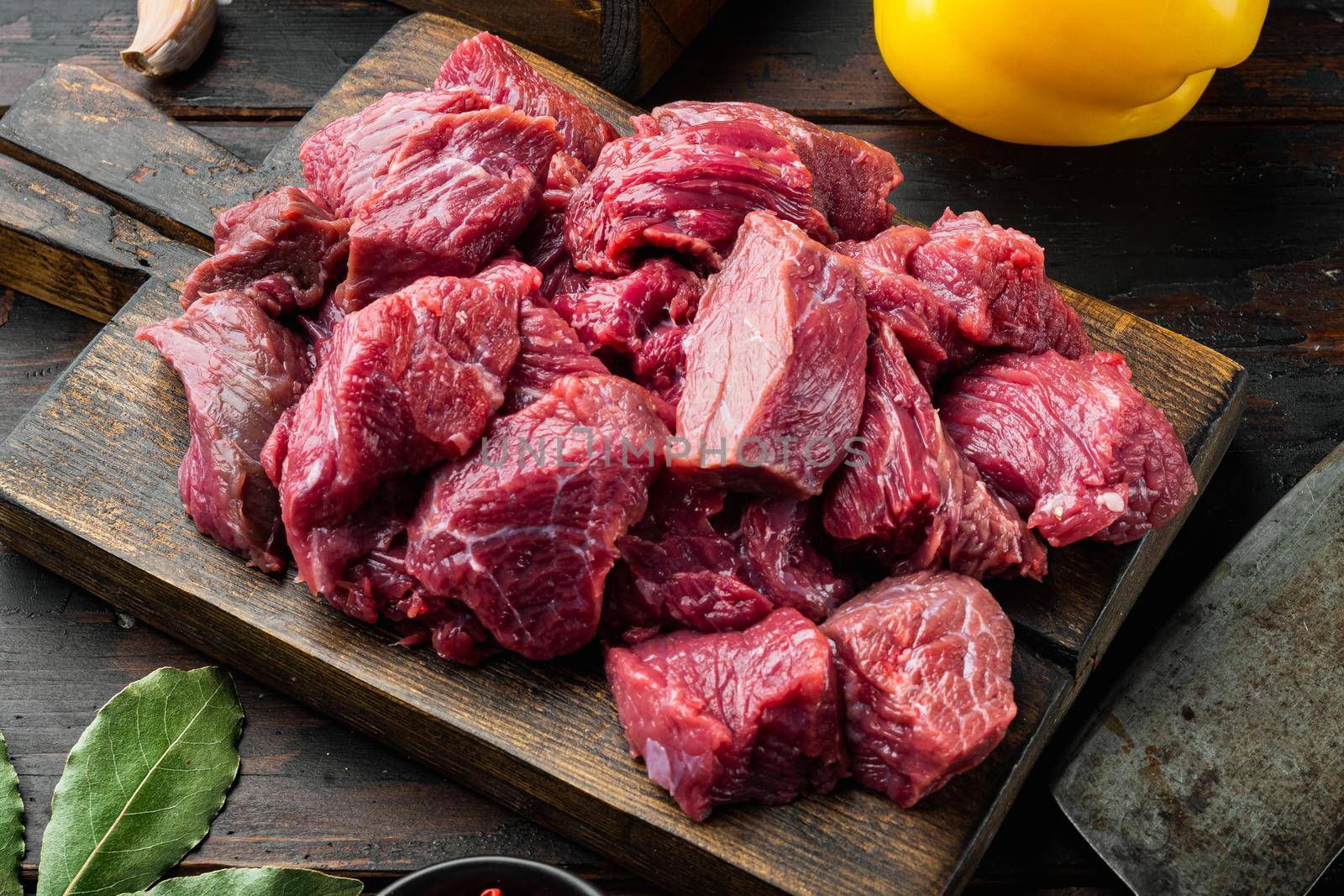 Fresh raw beef cubes with sweet bell pepper, on old dark wooden table by Ilianesolenyi