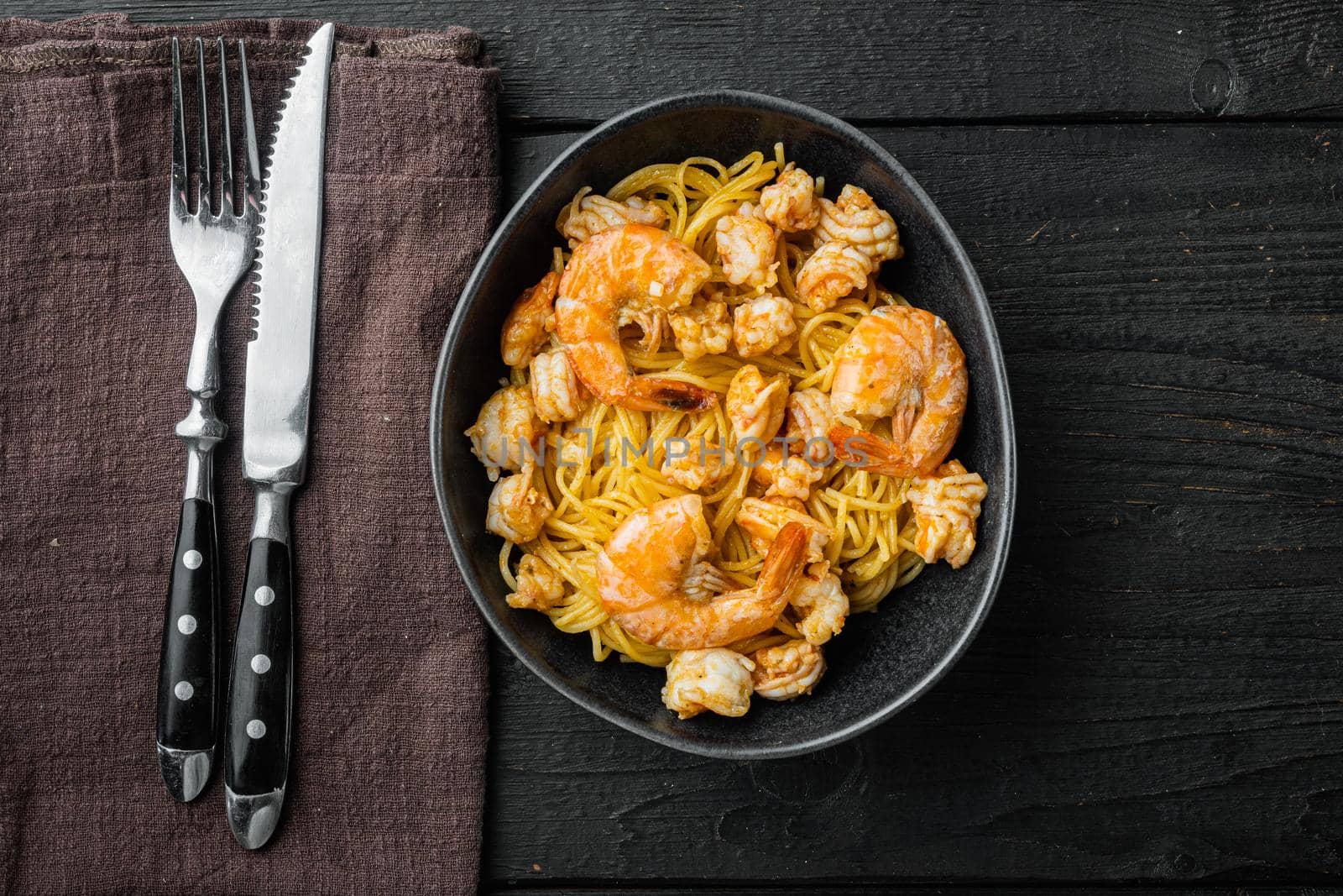 Noodles with seafood set, in bowl, on black wooden background, top view flat lay