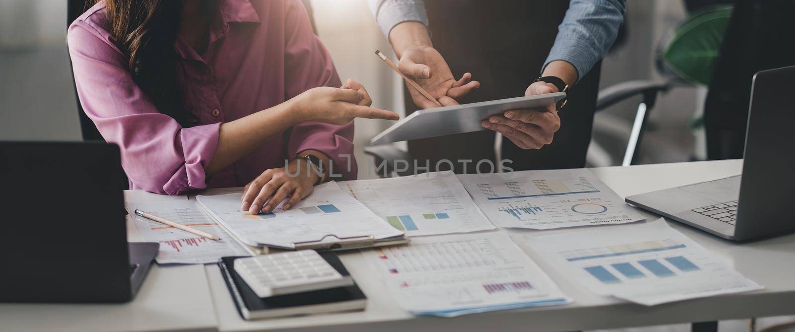 Close up business adviser partnership coworkers using a tablet to chart company financial statements report and profits work progress and planning in office room.
