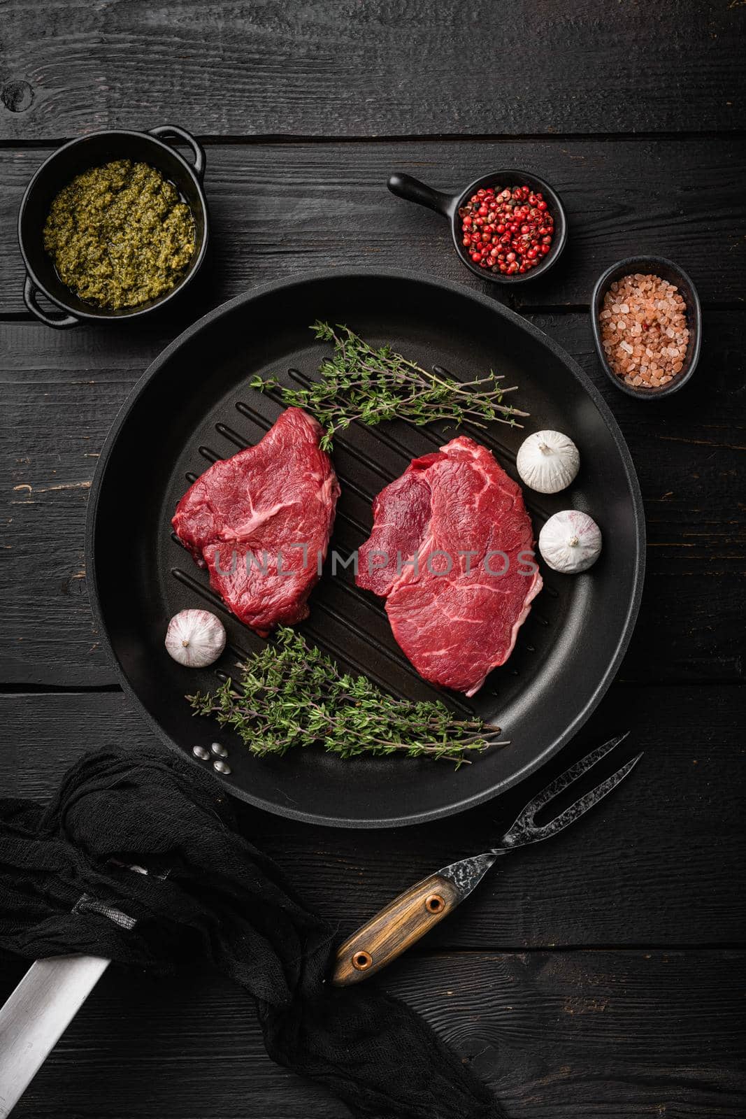 Raw seasoned rump steaks beef meat, on black wooden table background, top view flat lay by Ilianesolenyi