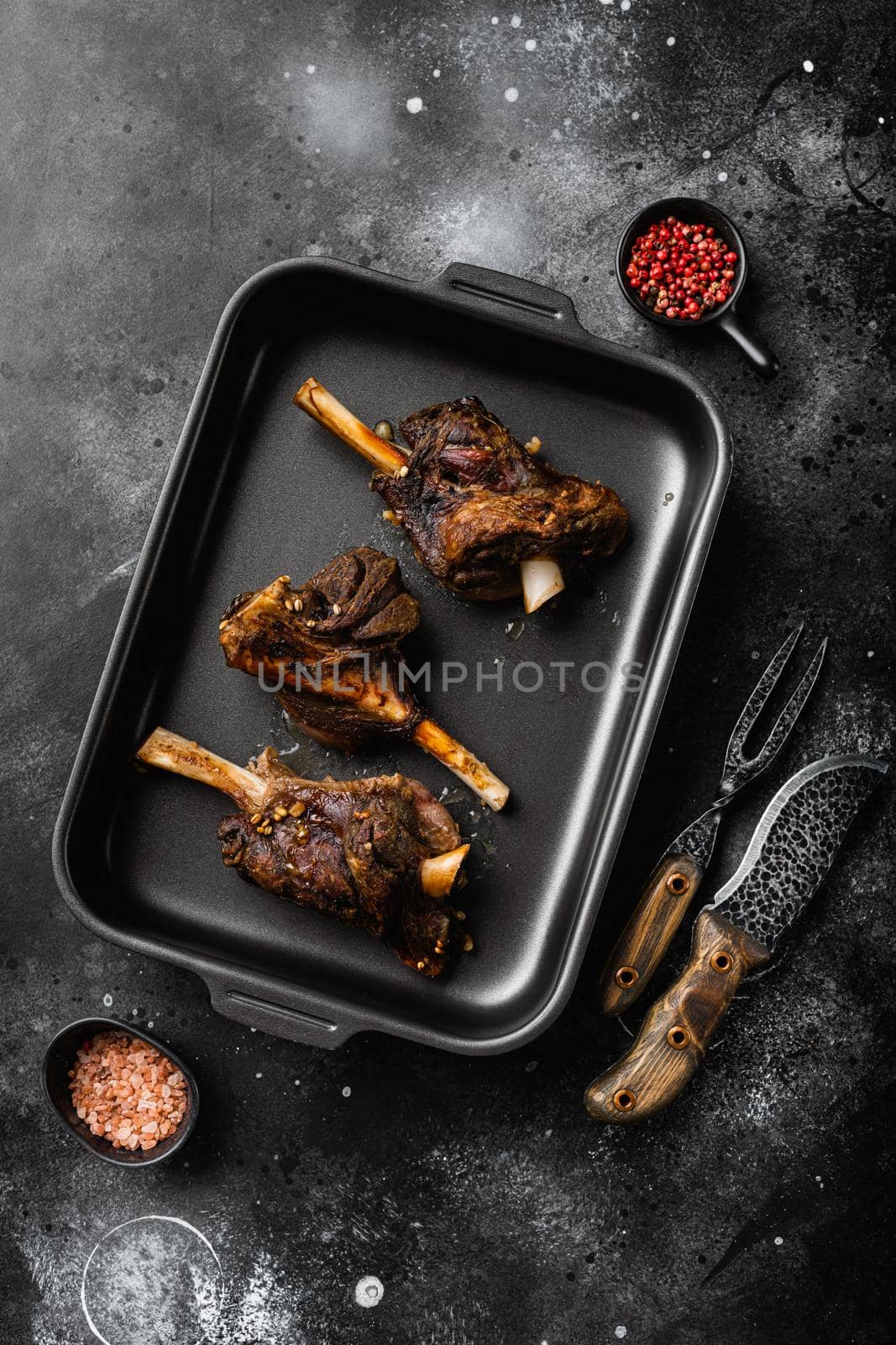 Slow Cooked Lamb Shanks meat set, on black dark stone table background, top view flat lay