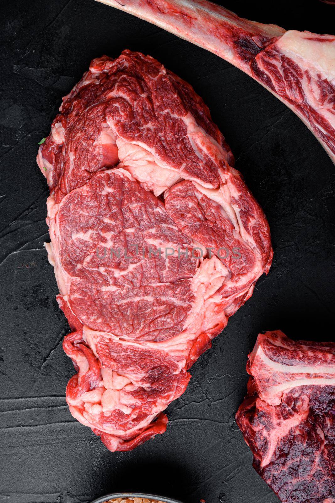 Black Angus prime beef rib eye steak, marbled meat set, on black stone background, top view flat lay