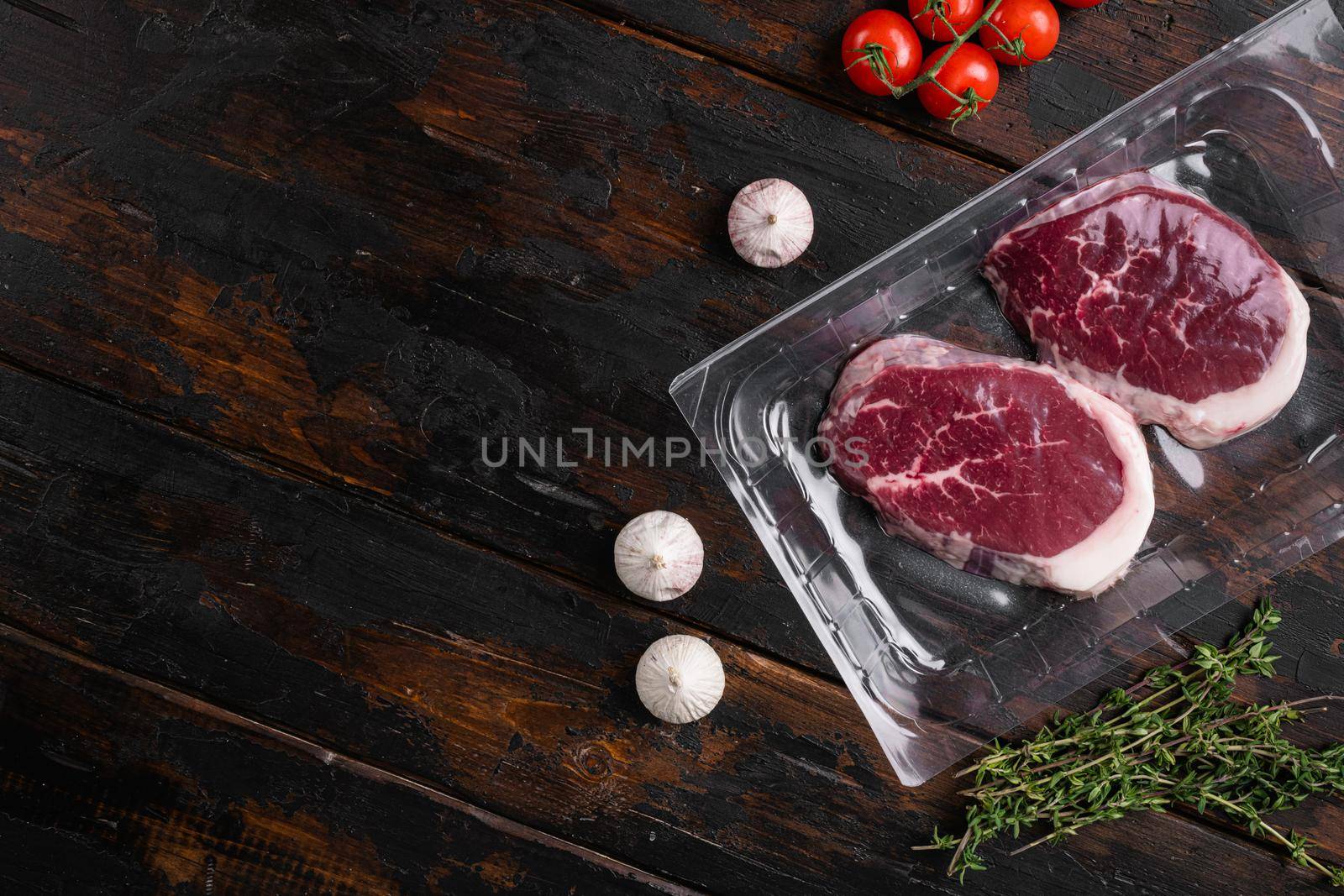 Vacuum market packed meat set, on old dark wooden table background, with copy space for text