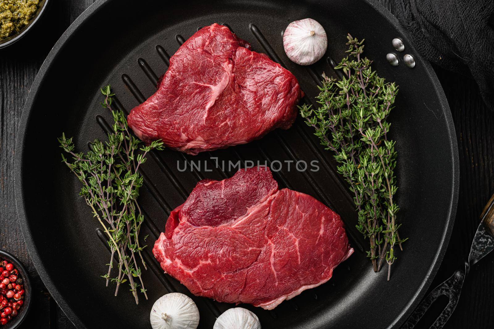 Raw beef meat steak with herbs set, on black wooden table background, top view flat lay