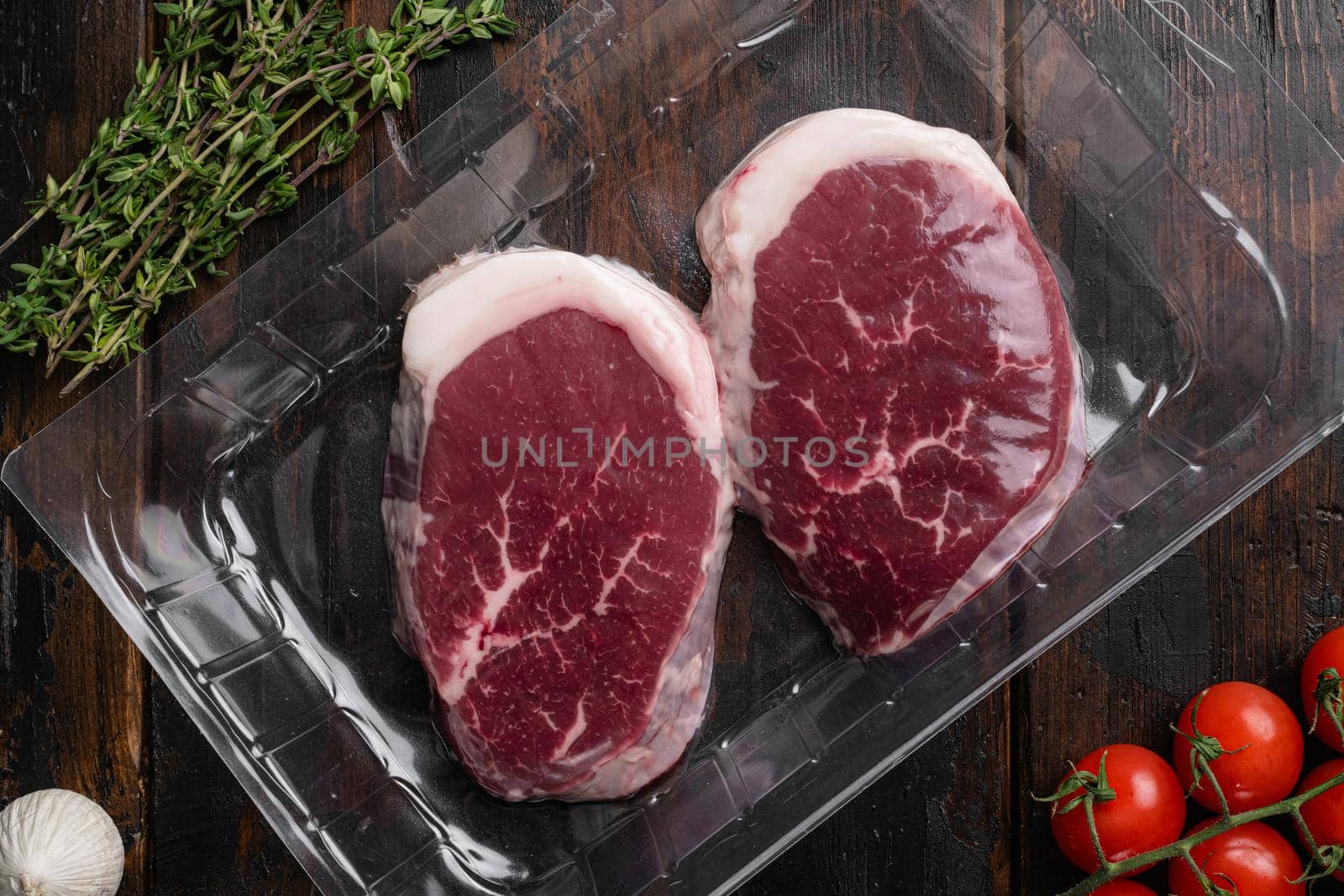 Beef steak vacuum sealed ready for cooking set, on old dark wooden table background, top view flat lay
