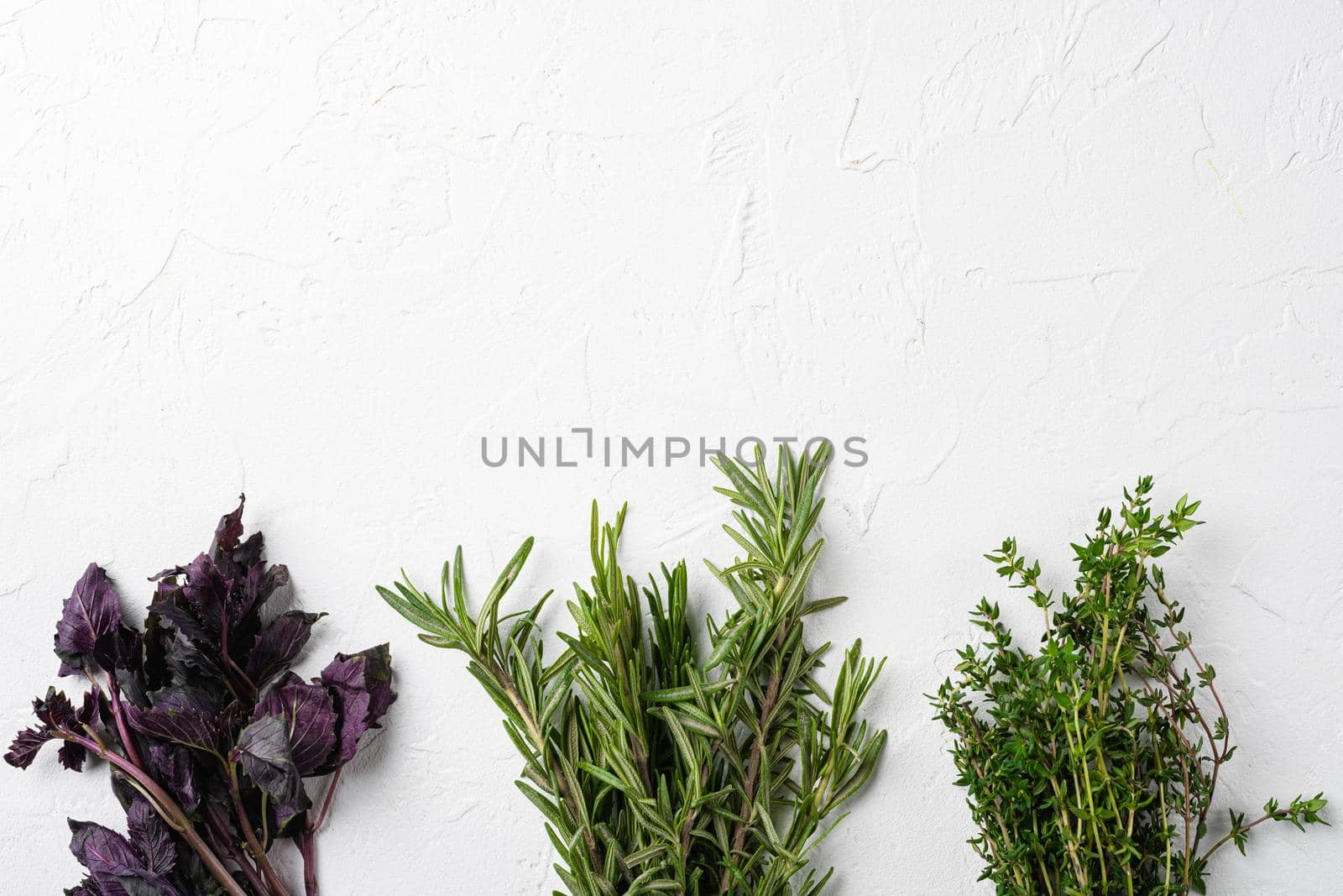 Garden fresh herbs rosemary, thyme, basil, on white stone table background, top view flat lay, with copy space for text by Ilianesolenyi