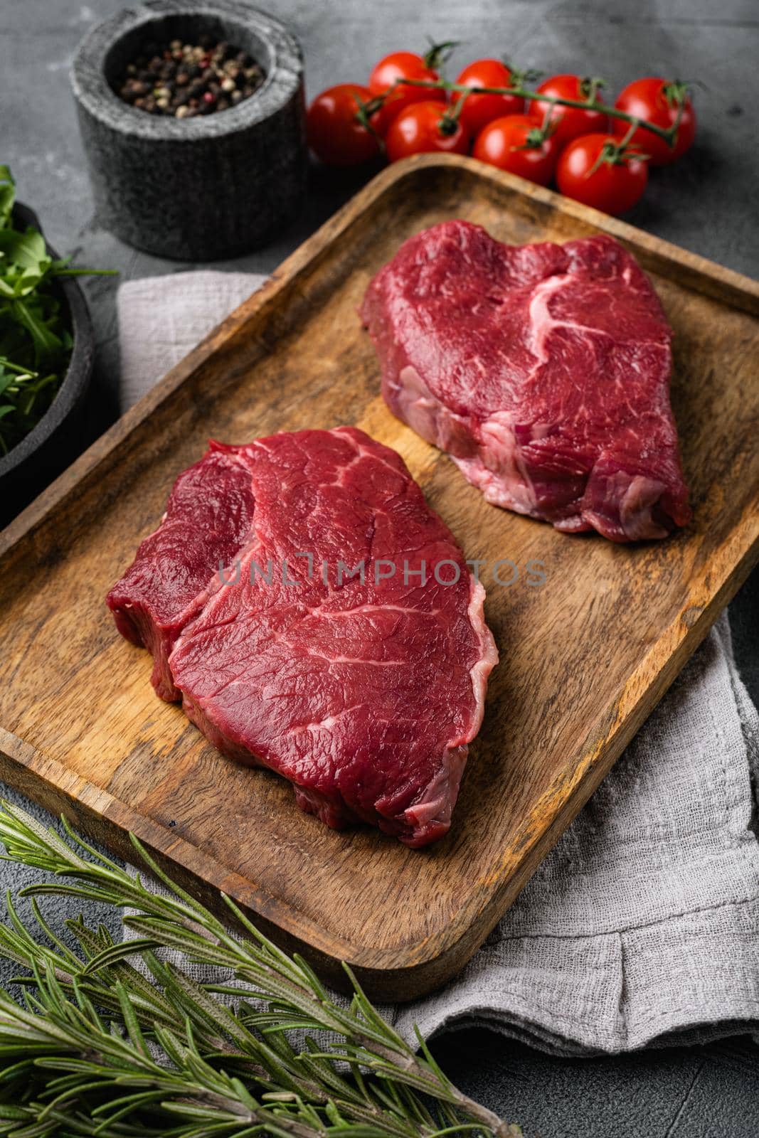 Raw beef meat steak with herbs, on gray stone table background by Ilianesolenyi