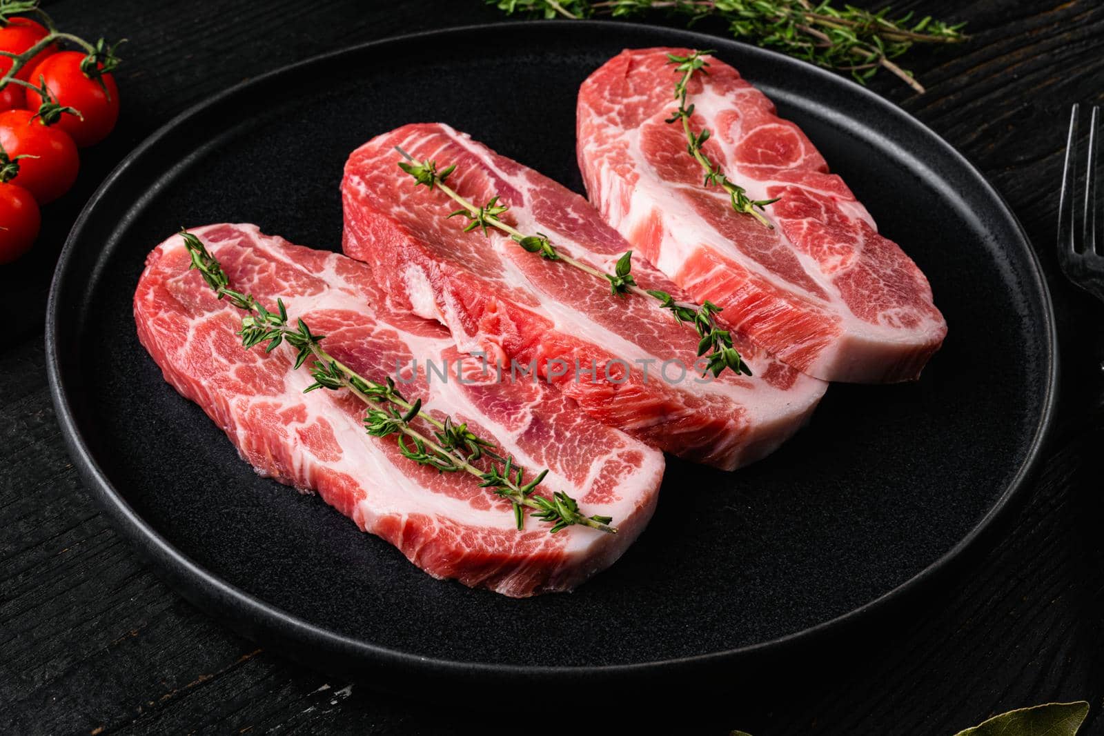 Fresh pork neck meat steaks set, on black wooden table background