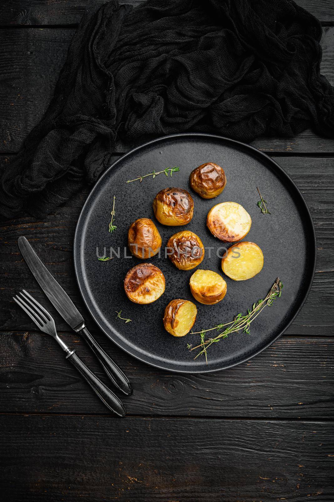 Baked potatoes set, on plate, on black wooden table background, top view flat lay