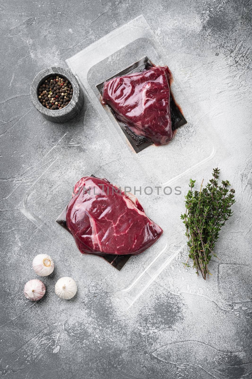 Pack with fresh rump beef steak set, on gray stone table background, top view flat lay