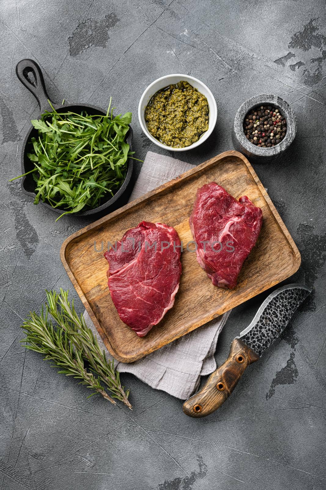 Beef raw rump steak with salt pepper rosemary, on gray stone table background, top view flat lay by Ilianesolenyi