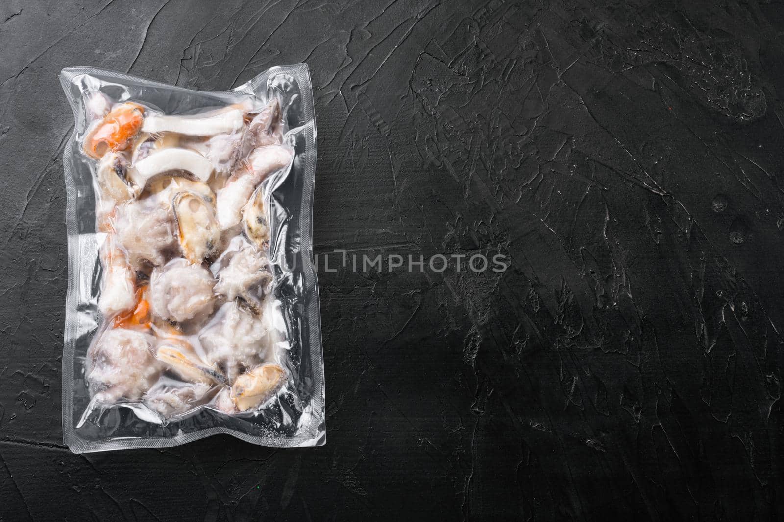 Raw seafood, mussels, squid octopus in vacuum pack set, on black dark stone table background, top view flat lay, with copy space for text