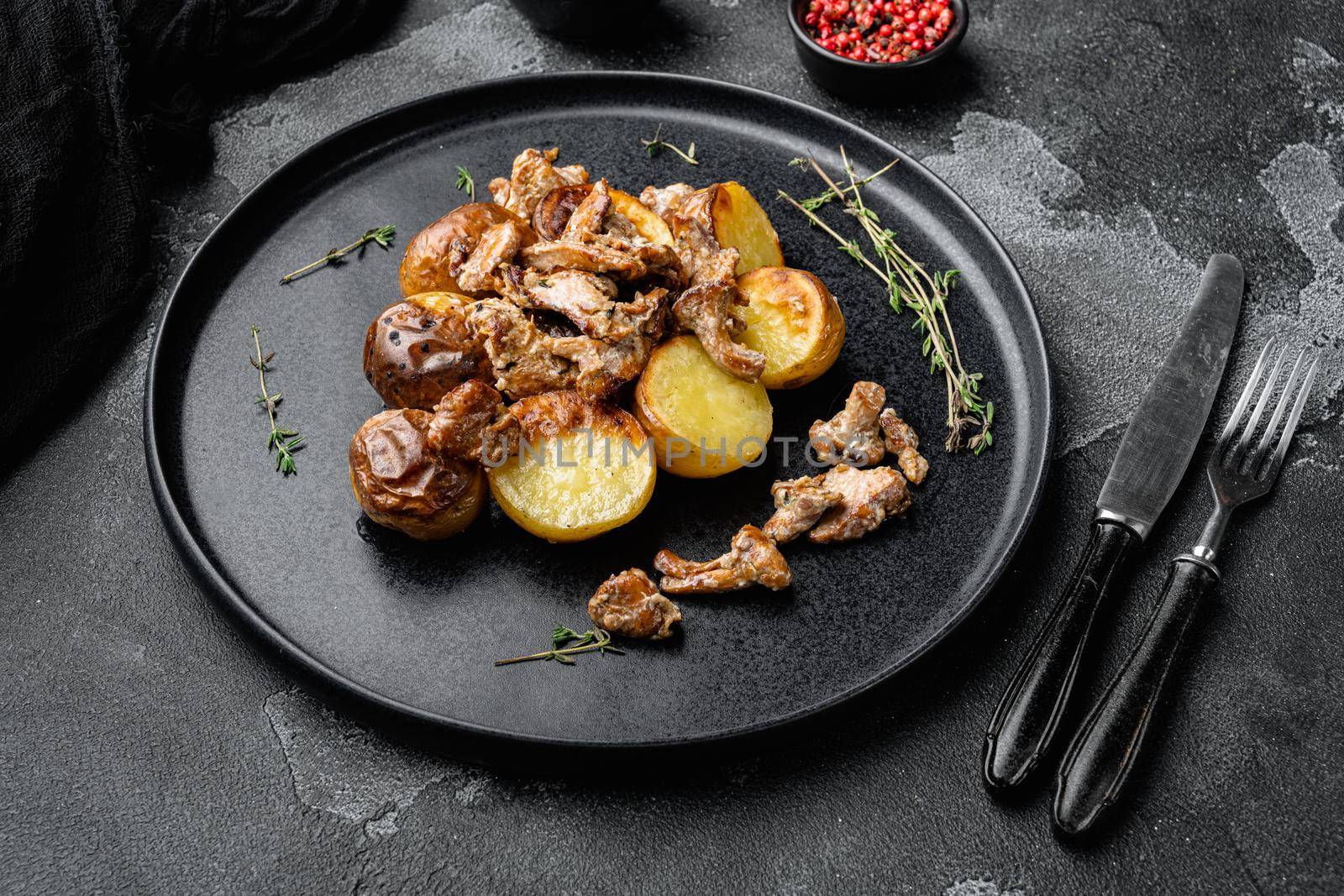 Potatoes with mushrooms, on black dark stone table background by Ilianesolenyi