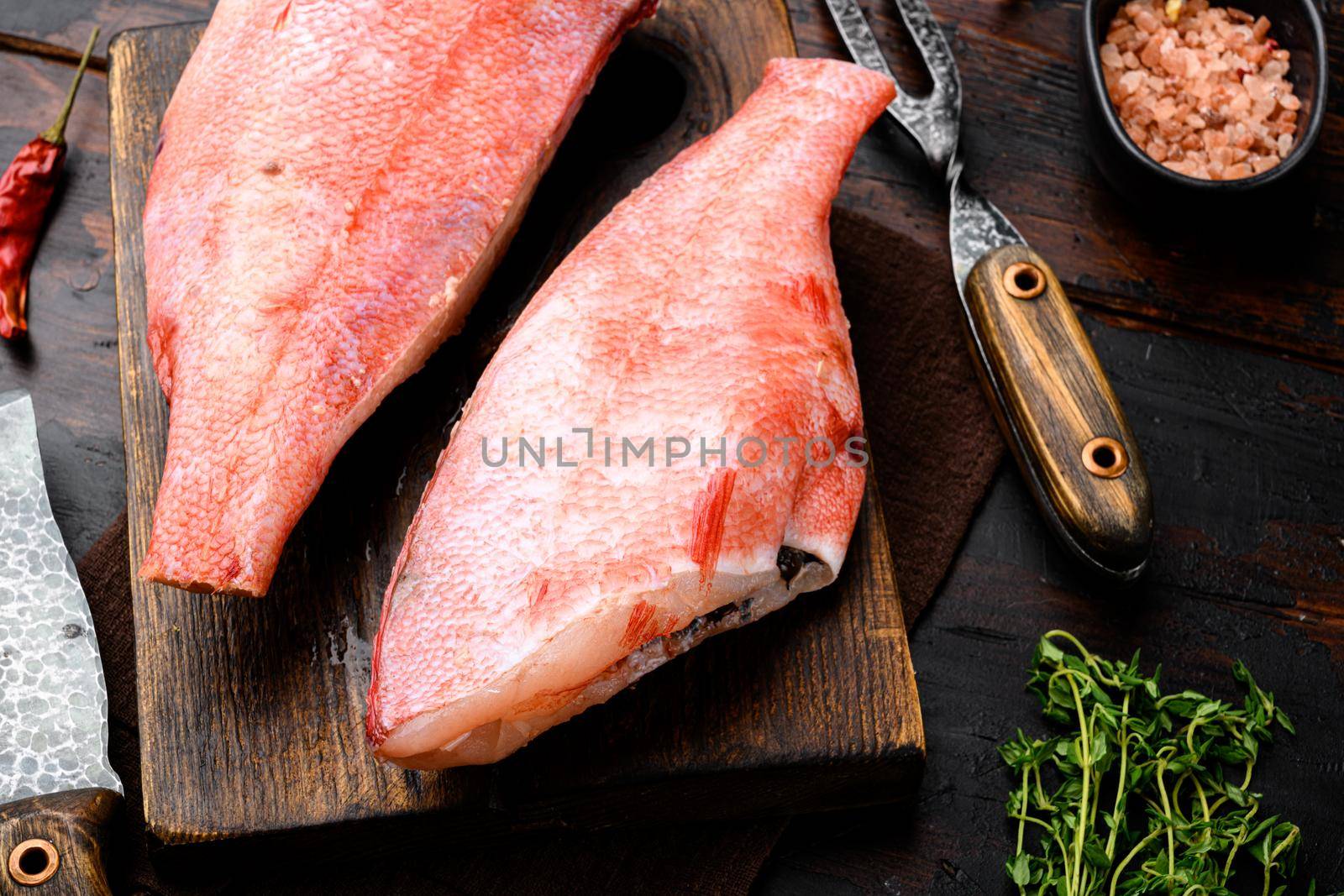 Raw fillet of red sea perch, on wooden cutting board, on old dark wooden table background by Ilianesolenyi