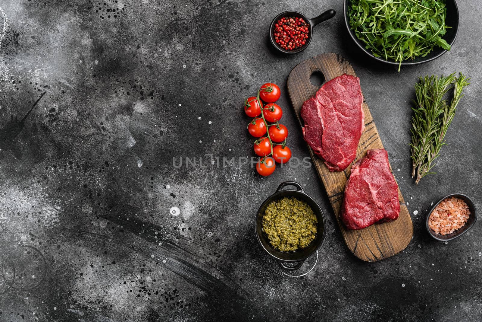 Raw cap rump steak set, on black dark stone table background, top view flat lay, with copy space for text