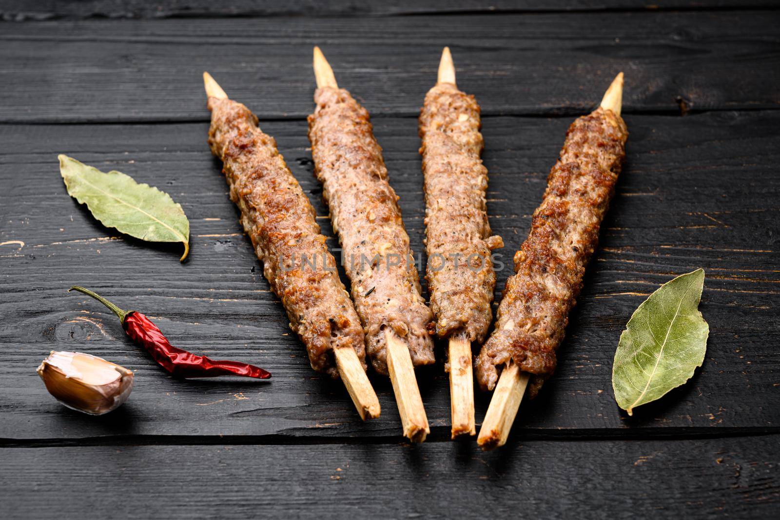 Mutton kebab shish skewers, on black wooden table background by Ilianesolenyi