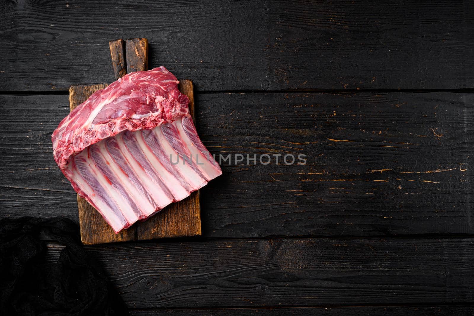 Organic Raw Lamb Chops set, on black wooden table background, top view flat lay, with copy space for text