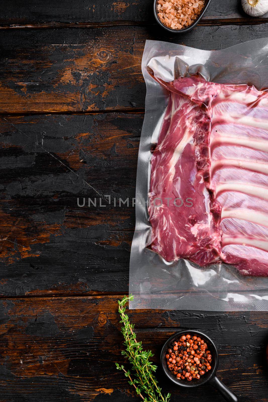 Lamb rib pack set, on old dark wooden table background, top view flat lay, with copy space for text