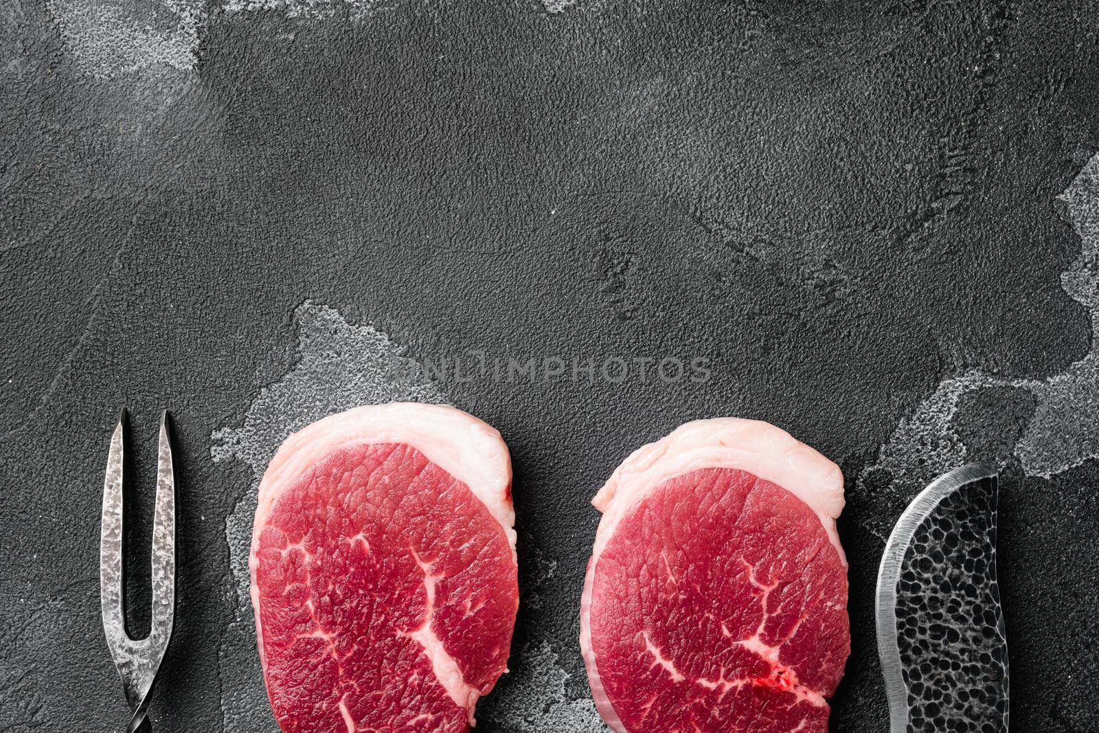 Fresh raw organic beef steak set, on black dark stone table background, top view flat lay, with copy space for text