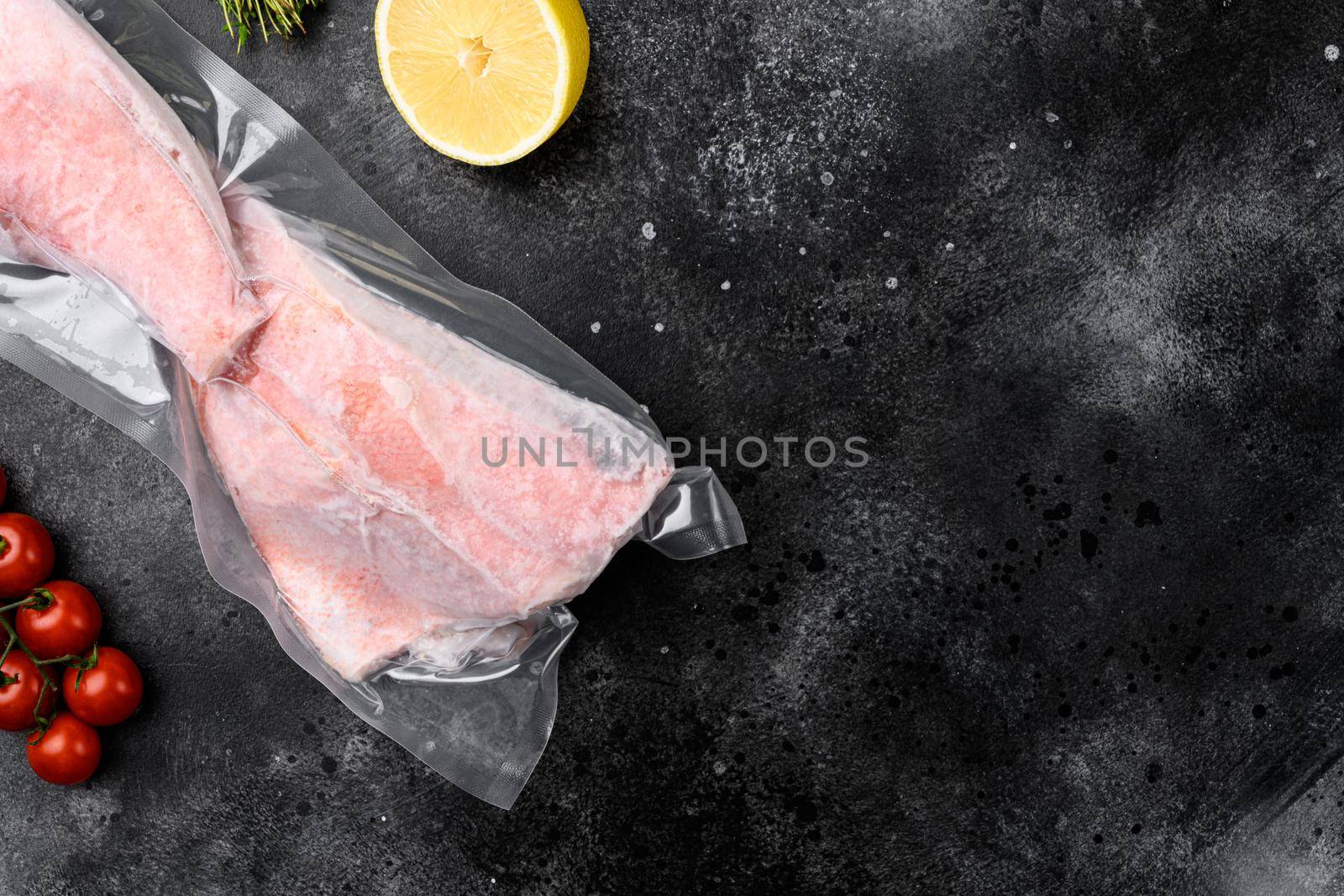 Orange roughy frozen pack fish meat, with herbs, on black dark stone table background, top view flat lay, with copy space for text by Ilianesolenyi