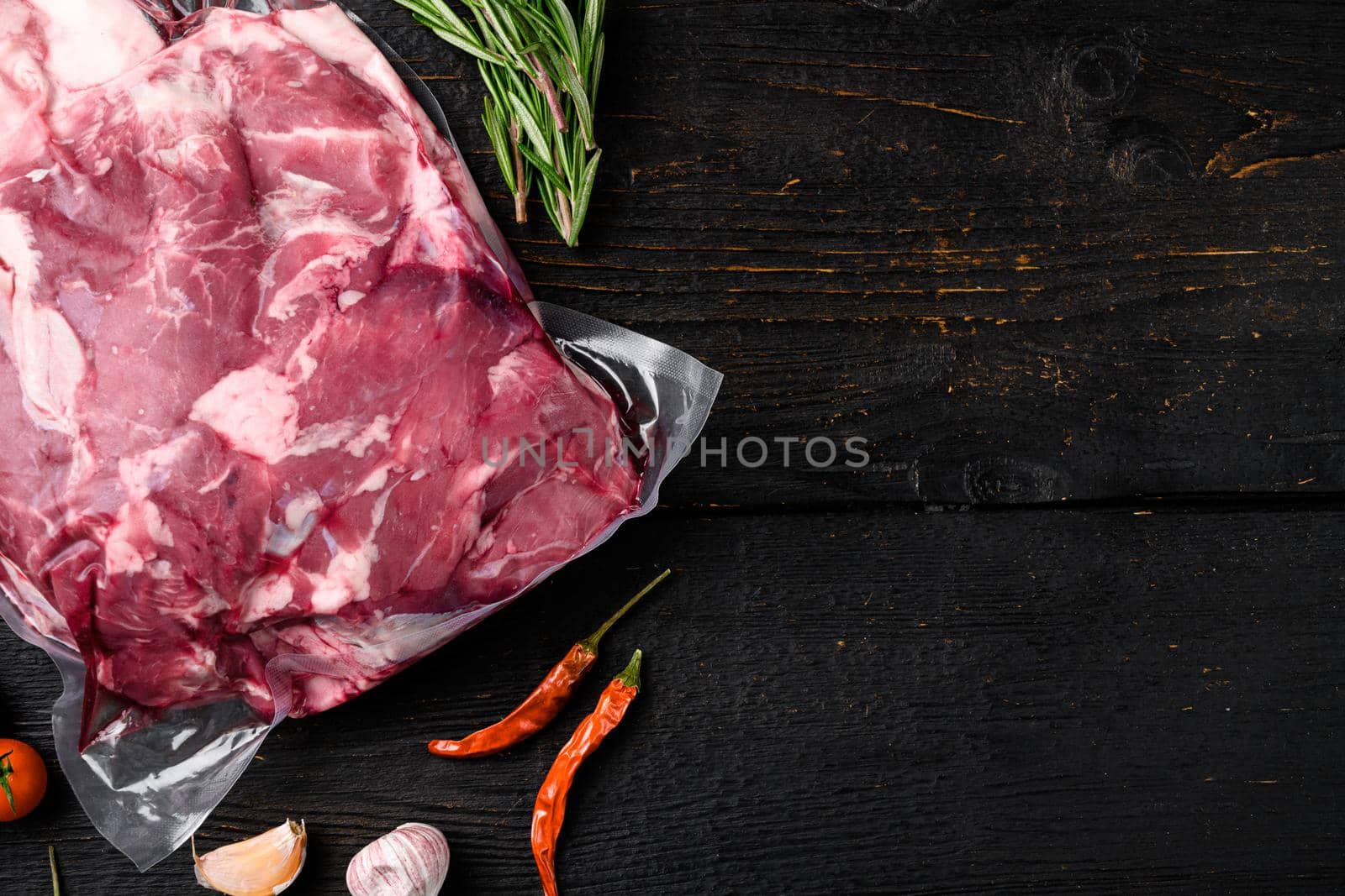 Lamb meat raw pack, with ingredients and herbs, on black wooden table background, top view flat lay, with copy space for text by Ilianesolenyi