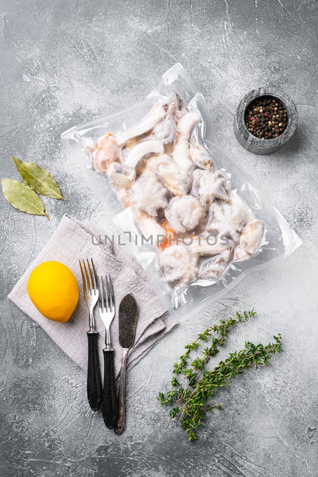 Raw seafood, mussels, squid octopus in vacuum pack set, on gray stone table background, top view flat lay