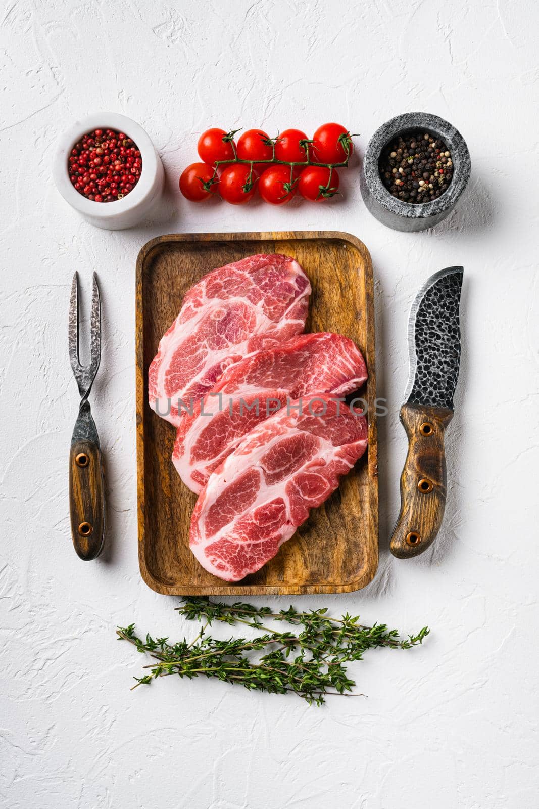 Raw pork neck chop meat with herb leaves and spice set, on white stone table background, top view flat lay