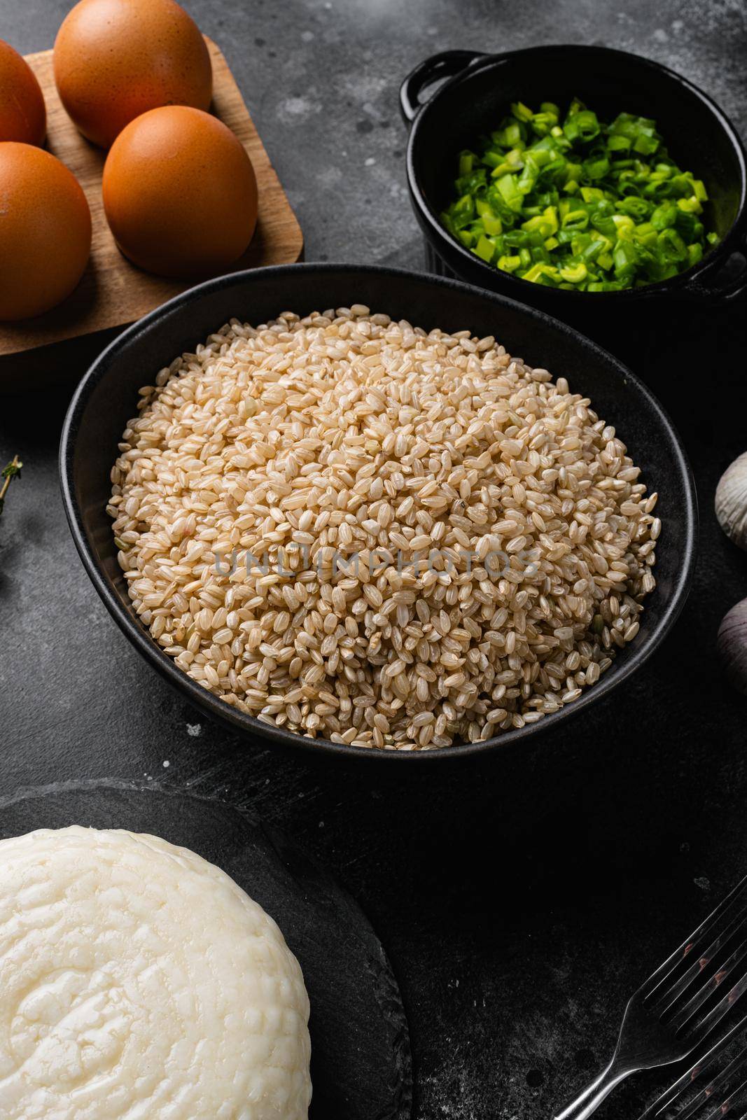 Ingredients for rice with cheese set, on black dark stone table background